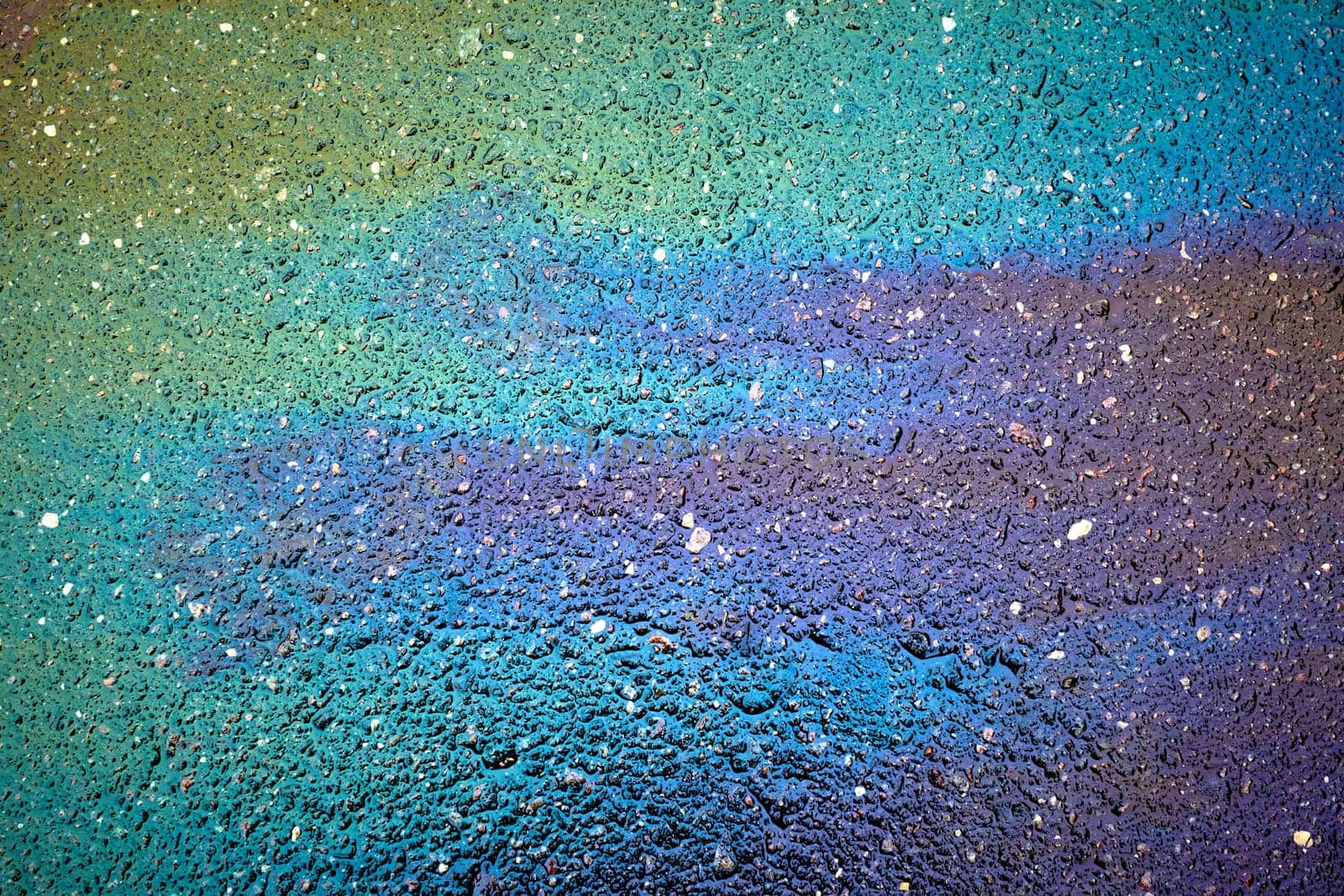 Gasoline creating rainbow chemical spill on asphalt road surface