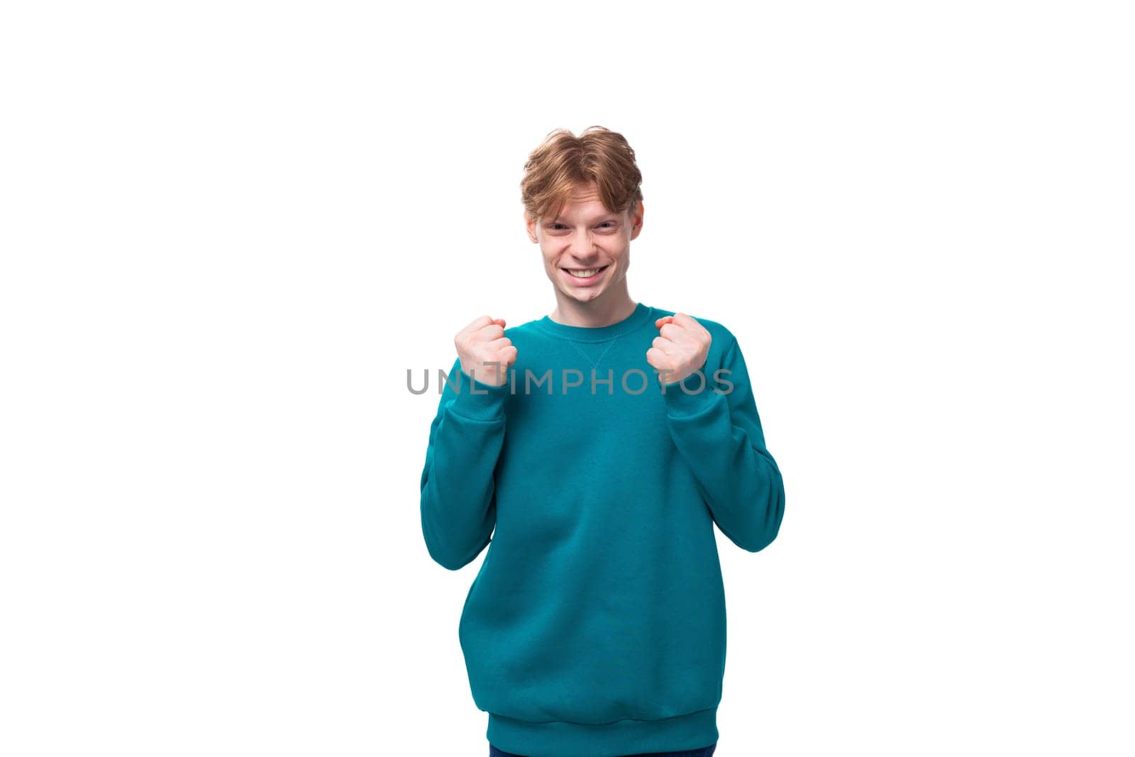young satisfied red-haired man with a blue sweater on a white background.