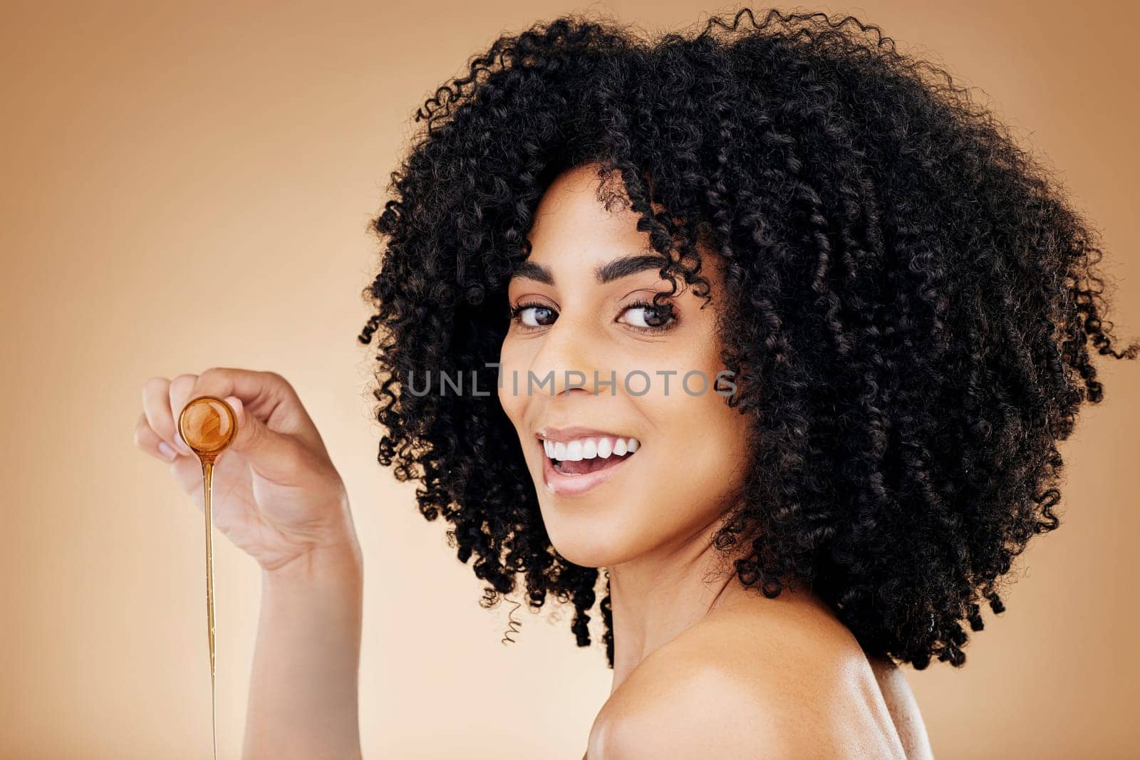 Hair, honey or oil with woman and beauty, natural cosmetics for growth and skin isolated on studio background. Health, haircare with texture and serum product, salon treatment and smile in portrait by YuriArcurs