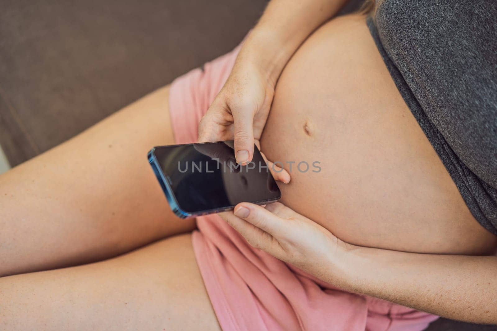 Pregnant girl with a smartphone. The concept of a negative impact on the unborn child in the womb. Violation of the nervous system of the child, reproductive.