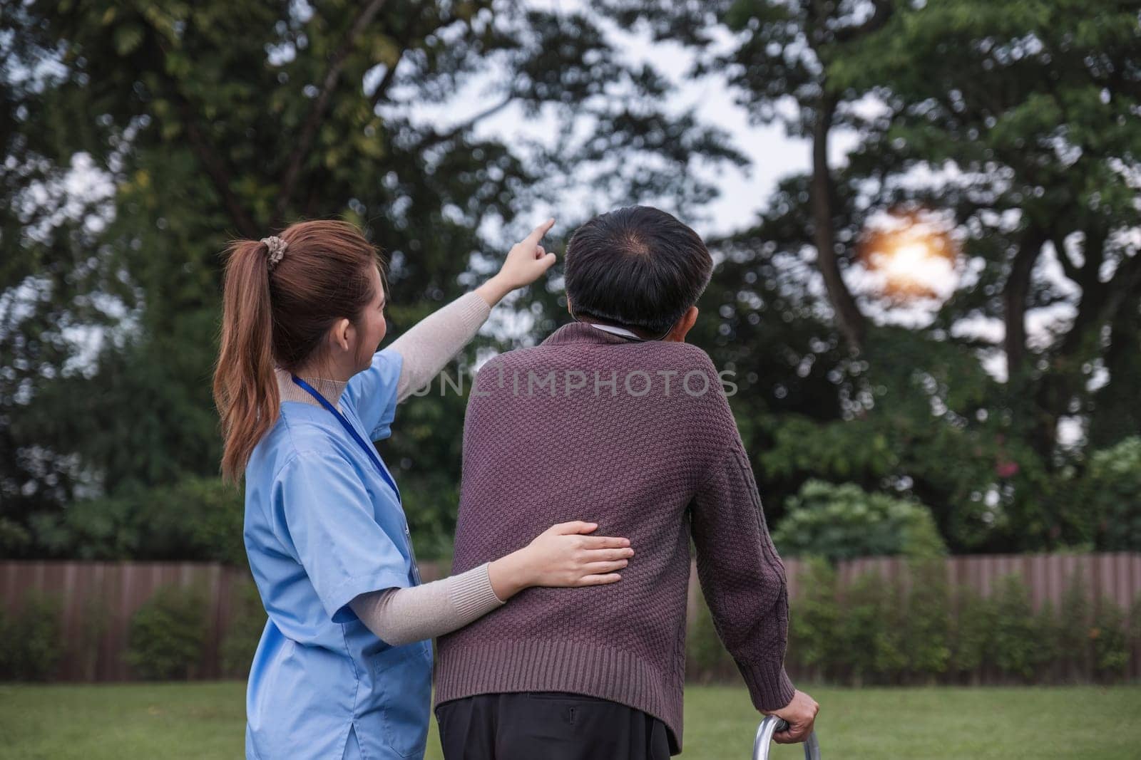 Asian woman caregiver helping senior man walking. Nurse assisting he old man patient at nursing home. Senior man using walker being helped by nurse at home. Elderly patient care and health lifestyle.