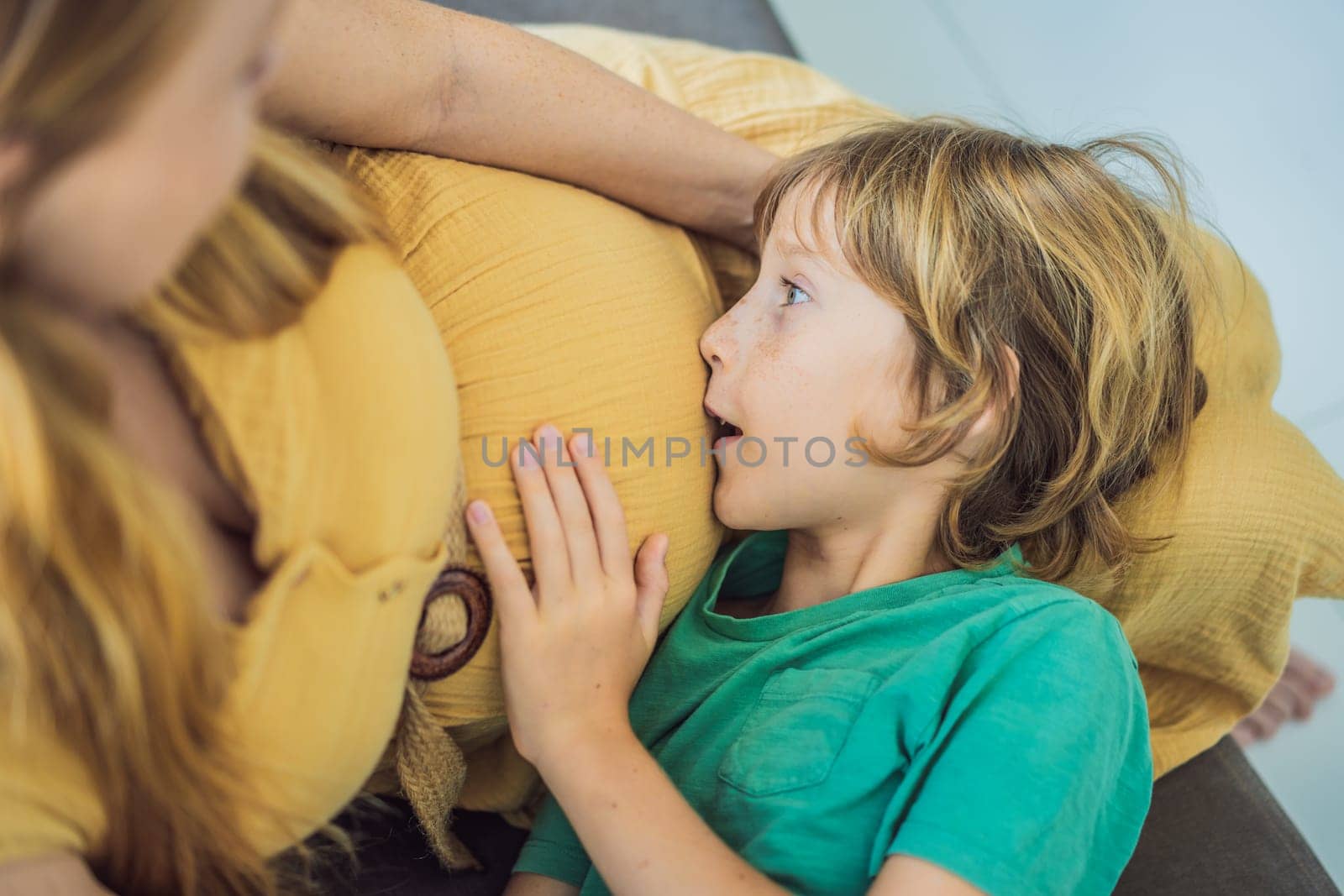 A heartwarming moment: pregnant mother and her older son sit on the sofa, engaging in a tender conversation about the upcoming pregnancy by galitskaya