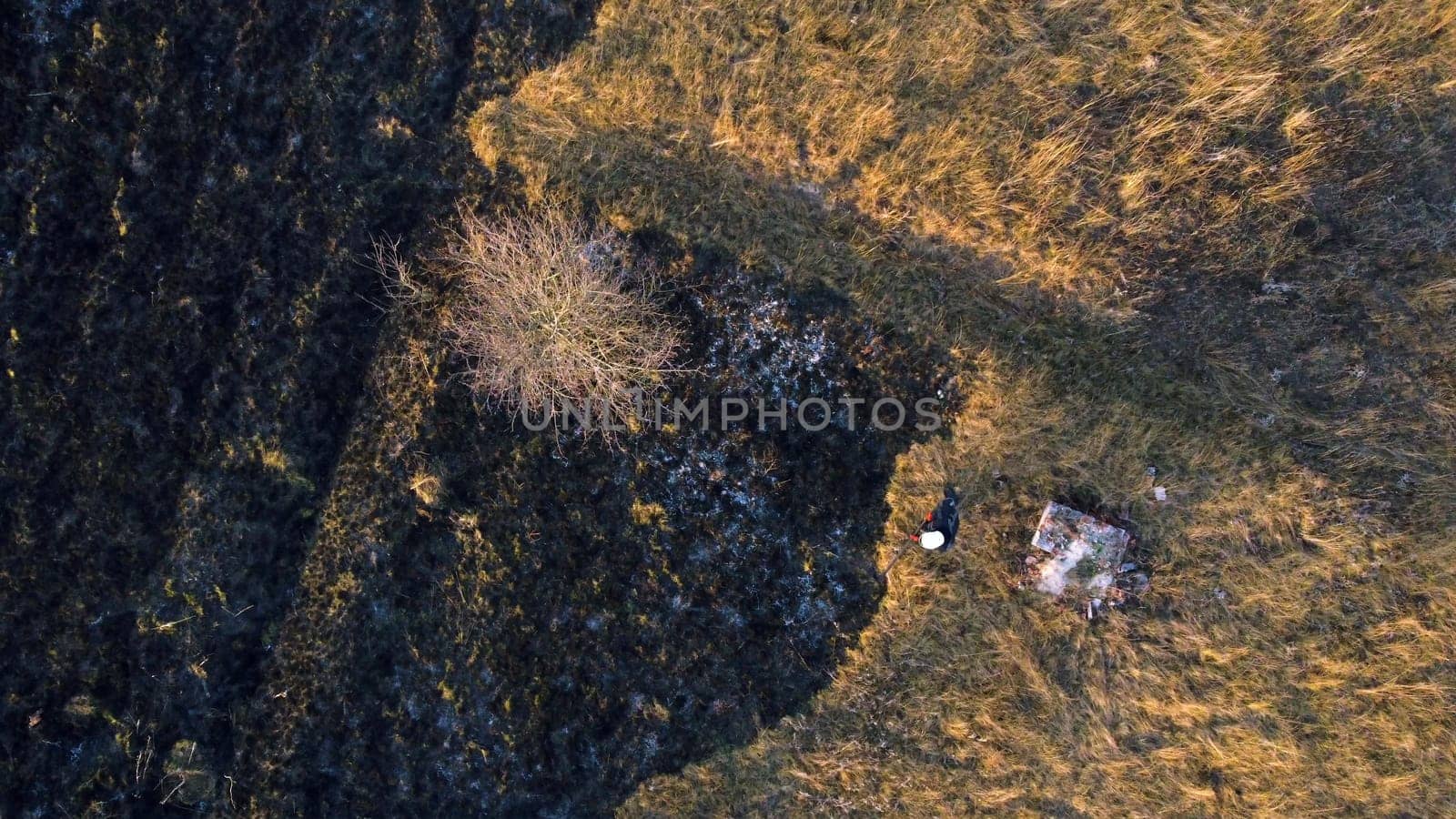 Aerial view Fire extinguishing. Fireman extinguishing burning dry grass. Open flames of fire and smoke. Yellow dry grass and black ash from burnt plants.Ecological catastrophy. Fire on field in steppe