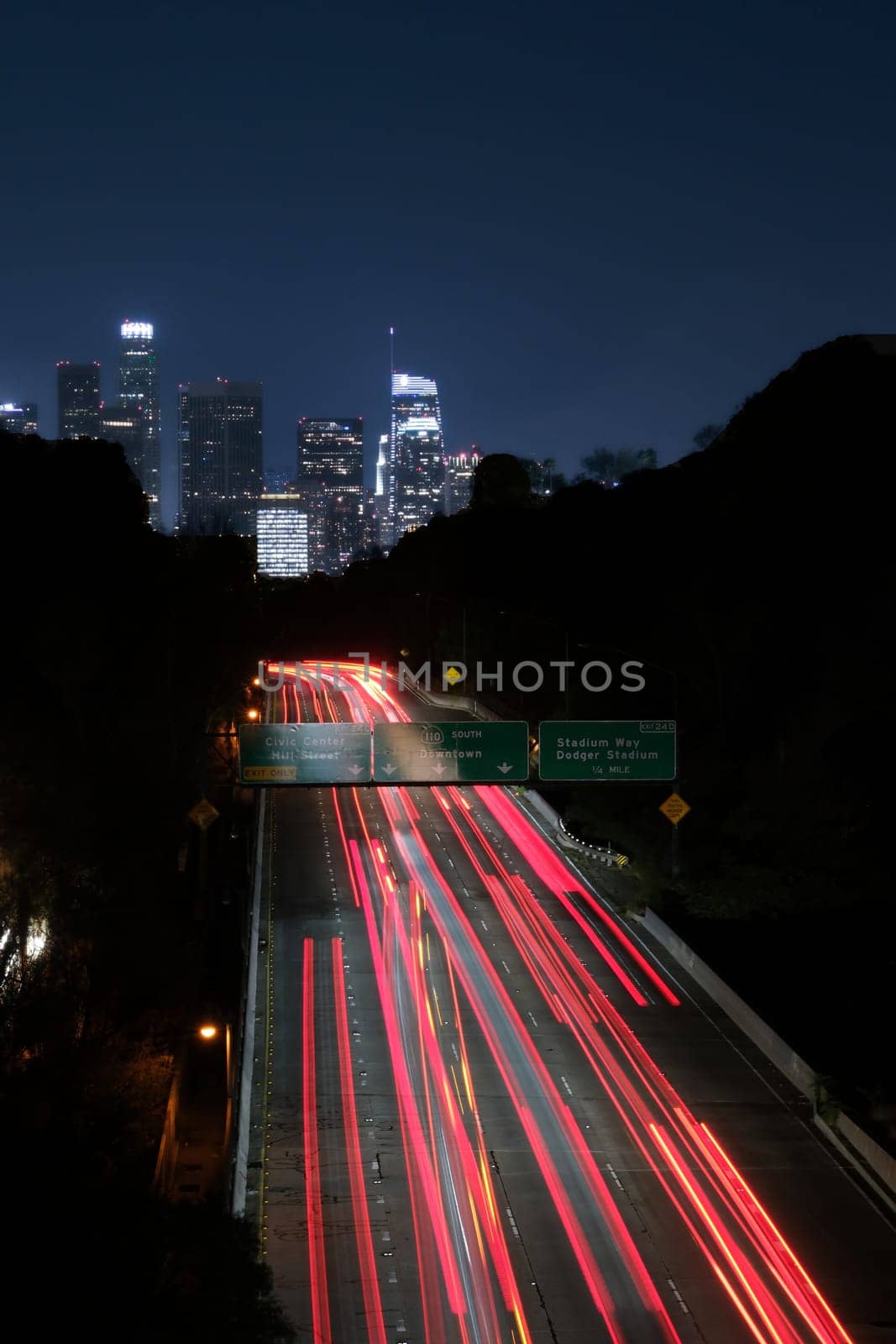 Los Angeles night exposure of red tail lights of freeway traffic toward downtown. Blue sky and red ribbon of light . High quality photo