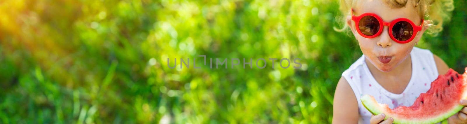 A child eats a watermelon in the park. Selective focus. by yanadjana