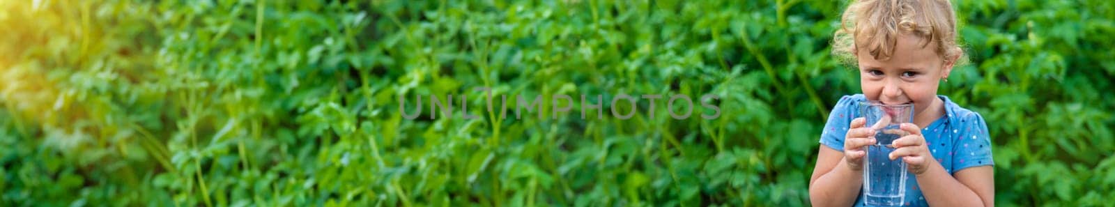 A child drinks water from a glass. Selective focus. by yanadjana