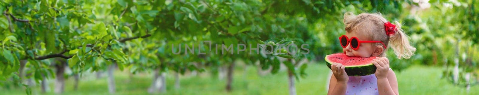 A child eats a watermelon in the park. Selective focus. by yanadjana