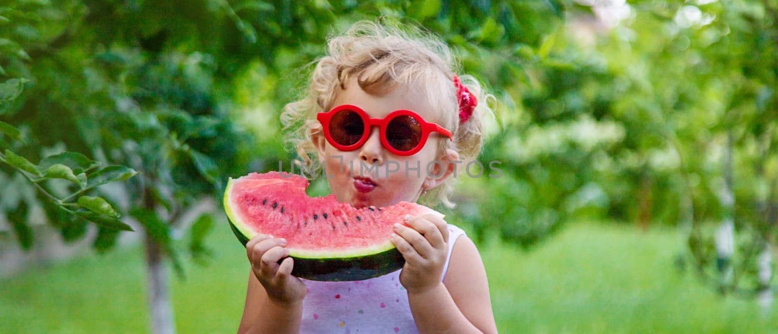 A child eats a watermelon in the park. Selective focus. Food.