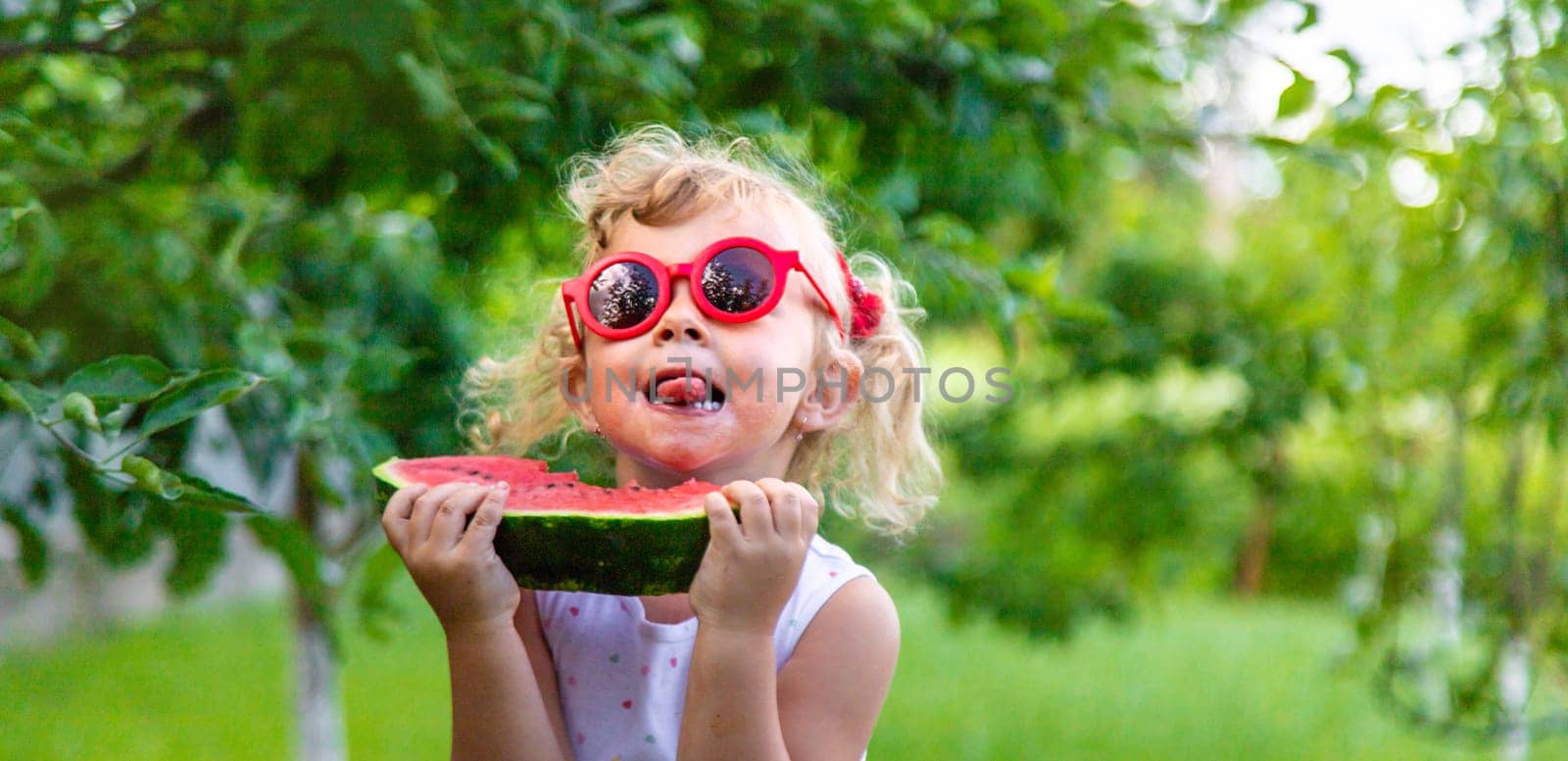 A child eats a watermelon in the park. Selective focus. Food.