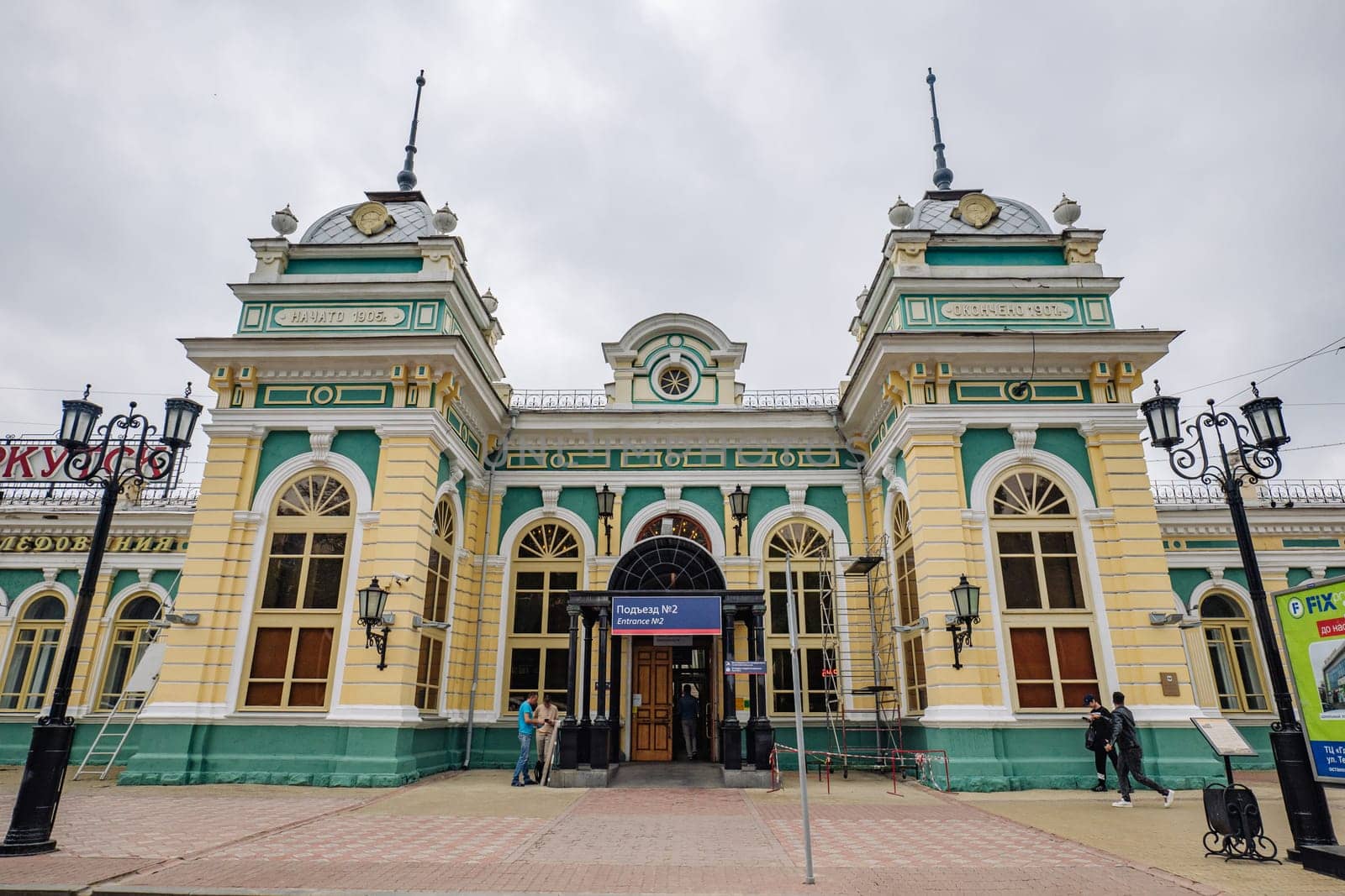 Tourists standing near nizhny novgorod railway station, featuring ornate architectural details and vibrant facade reflecting classic russian design aesthetics
