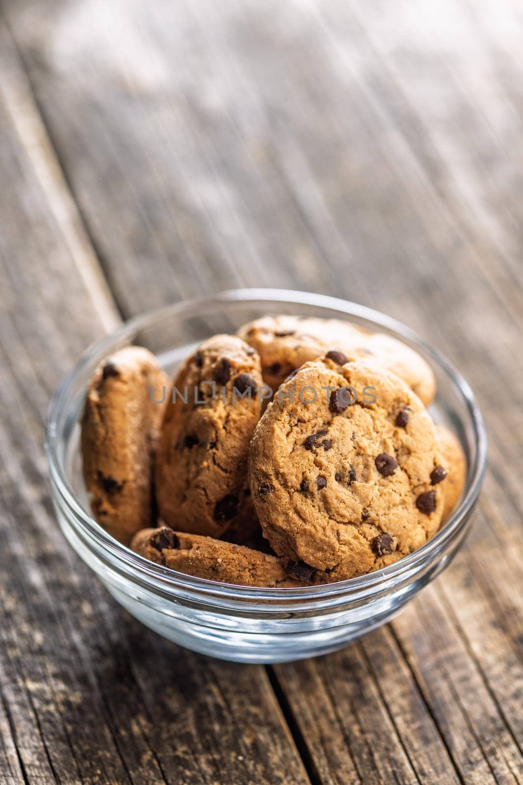 Chocolate chip cookies in bowl on a wooden table.