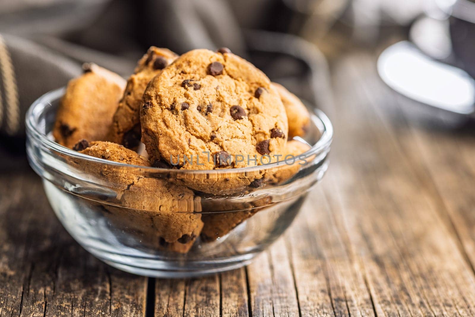 Chocolate chip cookies in bowl on a wooden table.