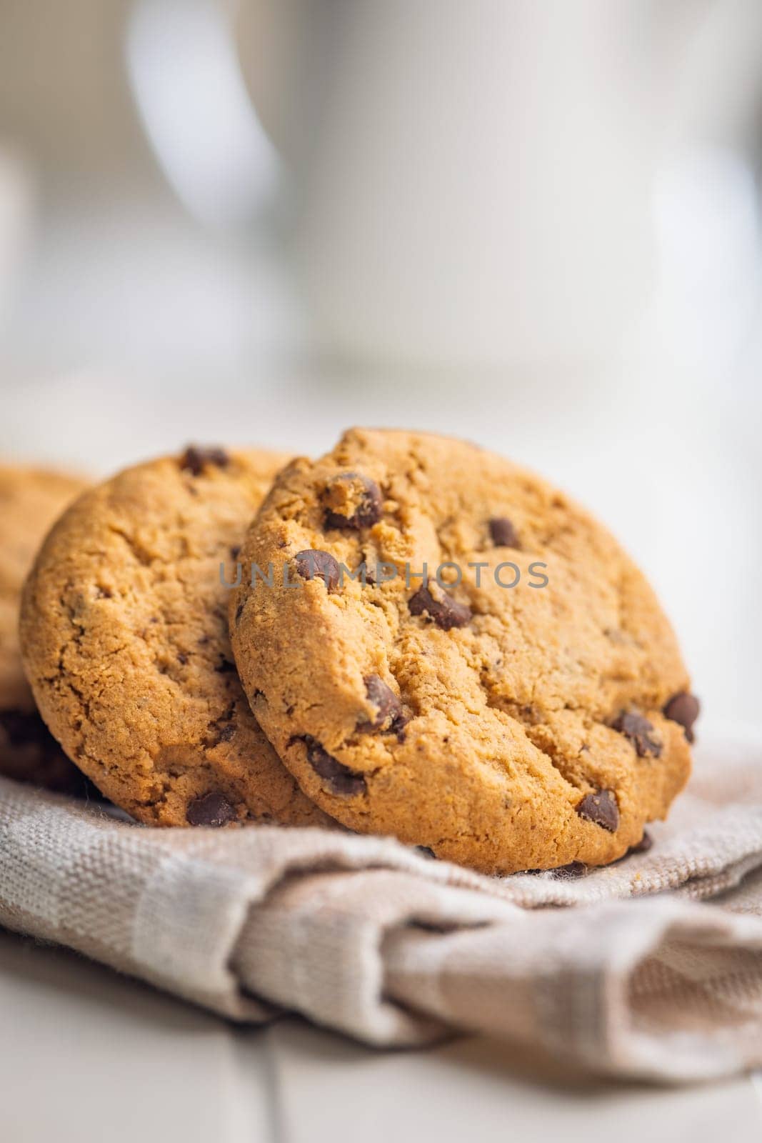 Chocolate chip cookies on napkin on a white table.