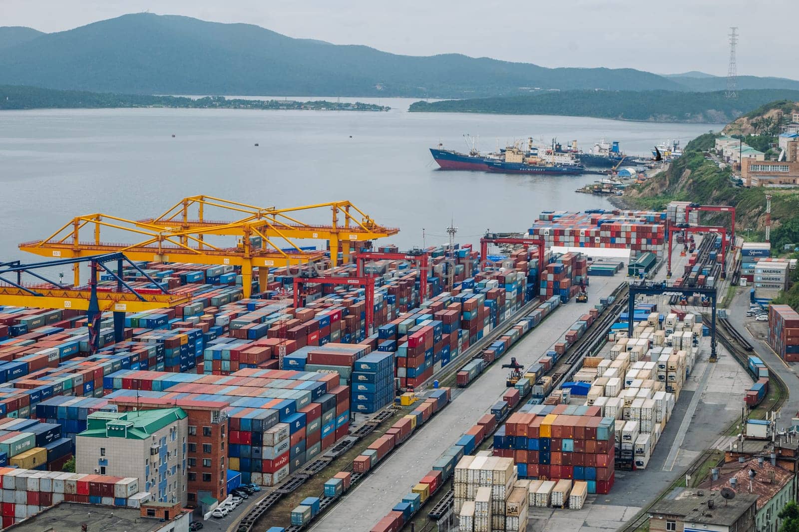 Freight trains carrying shipping containers near cargo cranes, illustrating global logistics and international trade transportation network