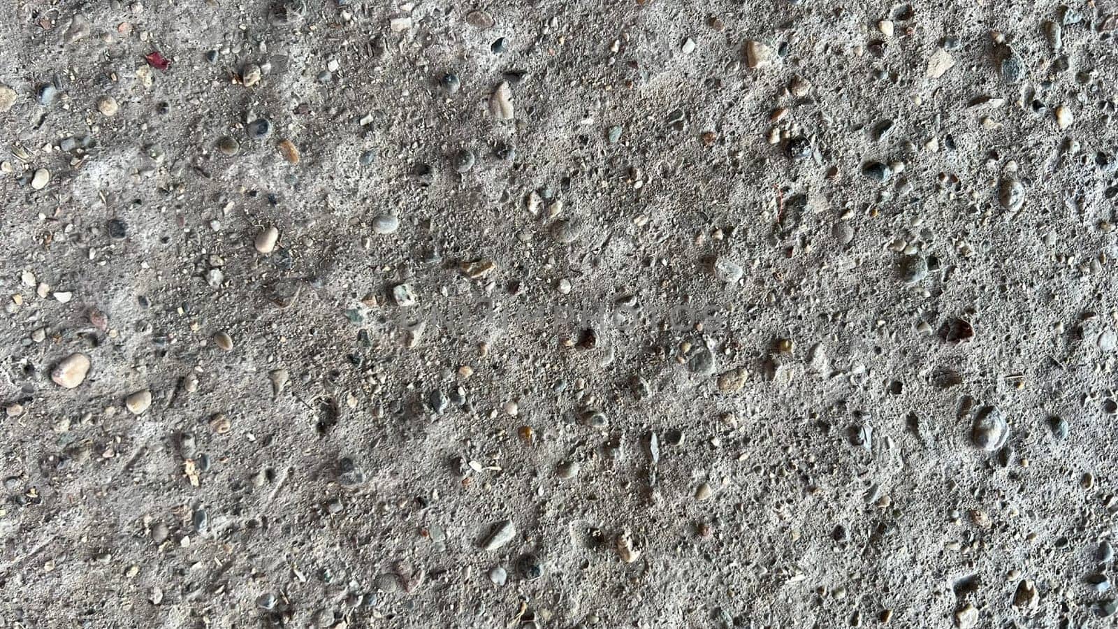 Close-up view of a concrete surface showcasing its rough texture and embedded stones.