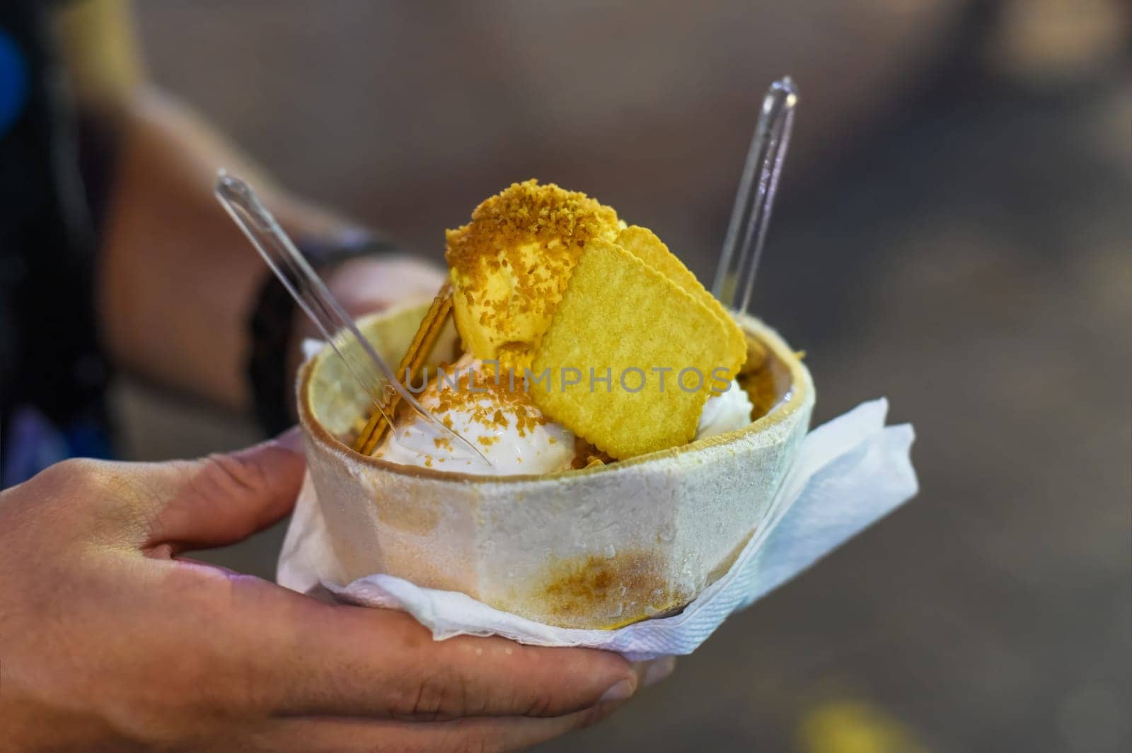 Hand holding coconut and mango ice cream in coconut shell in Jalan Alor street food market in Kuala Lumpur