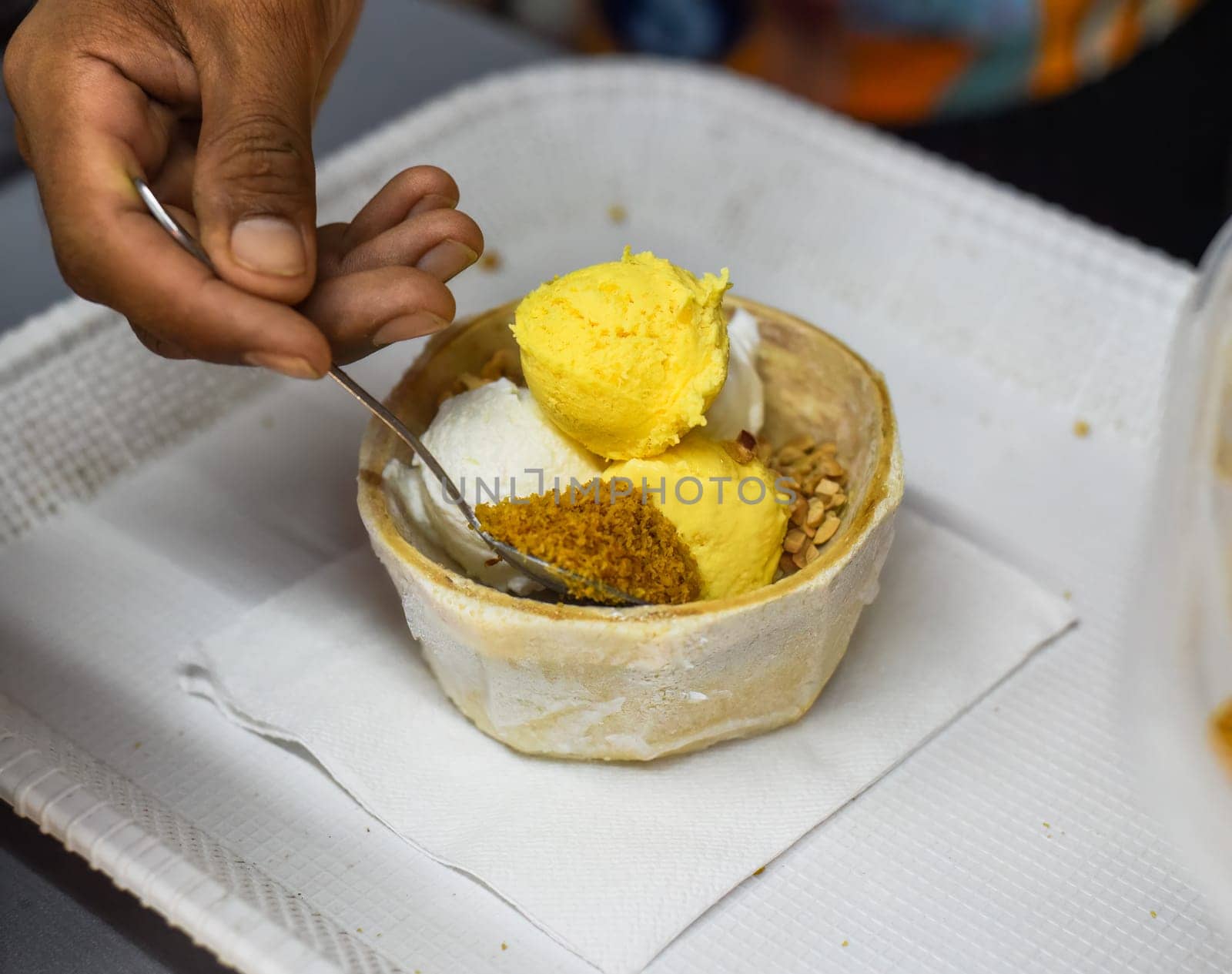 Hand holding coconut and mango ice cream in coconut shell in Jalan Alor street food market in Kuala Lumpur