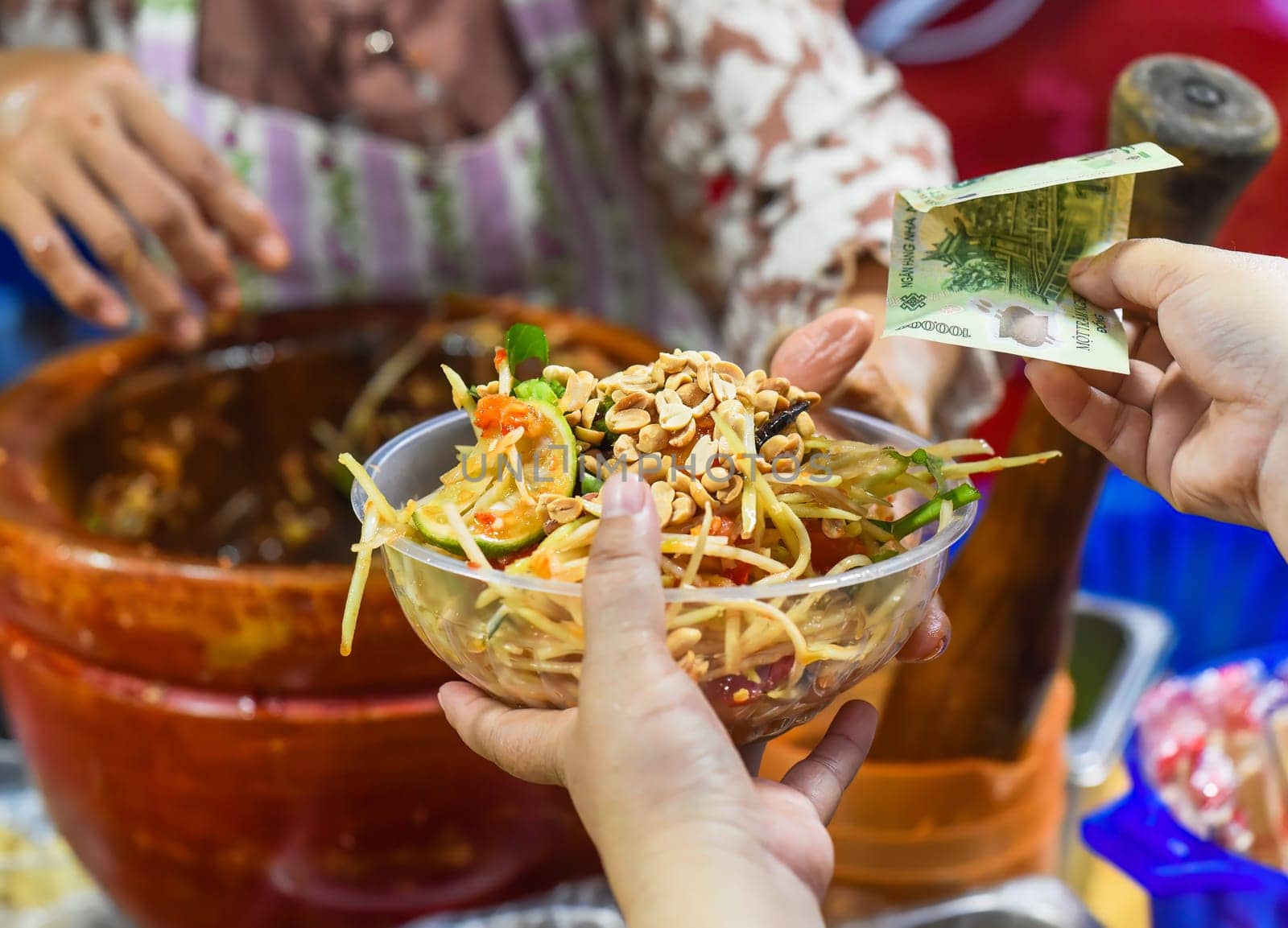 Vietnamese woman serving noodles with vegetables in vietnamese night market in food festival, person buying