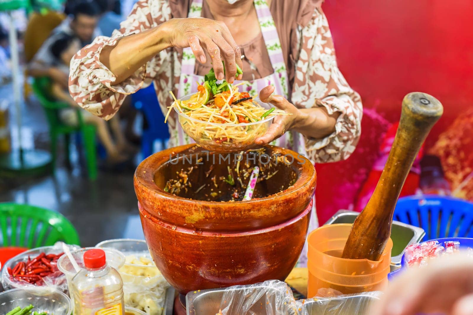 Vietnamese woman serving noodles with vegetables in vietnamese night market in food festival