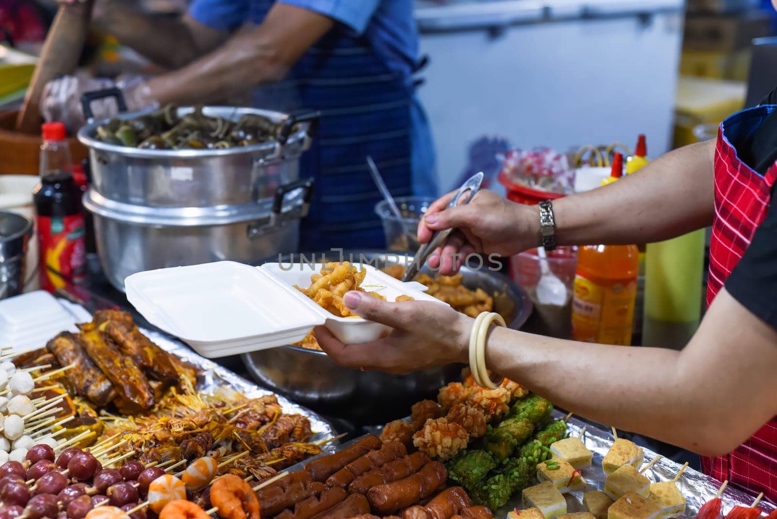 Vietnamese woman serving chicken paws in plastic box with chili in vietnamese night market