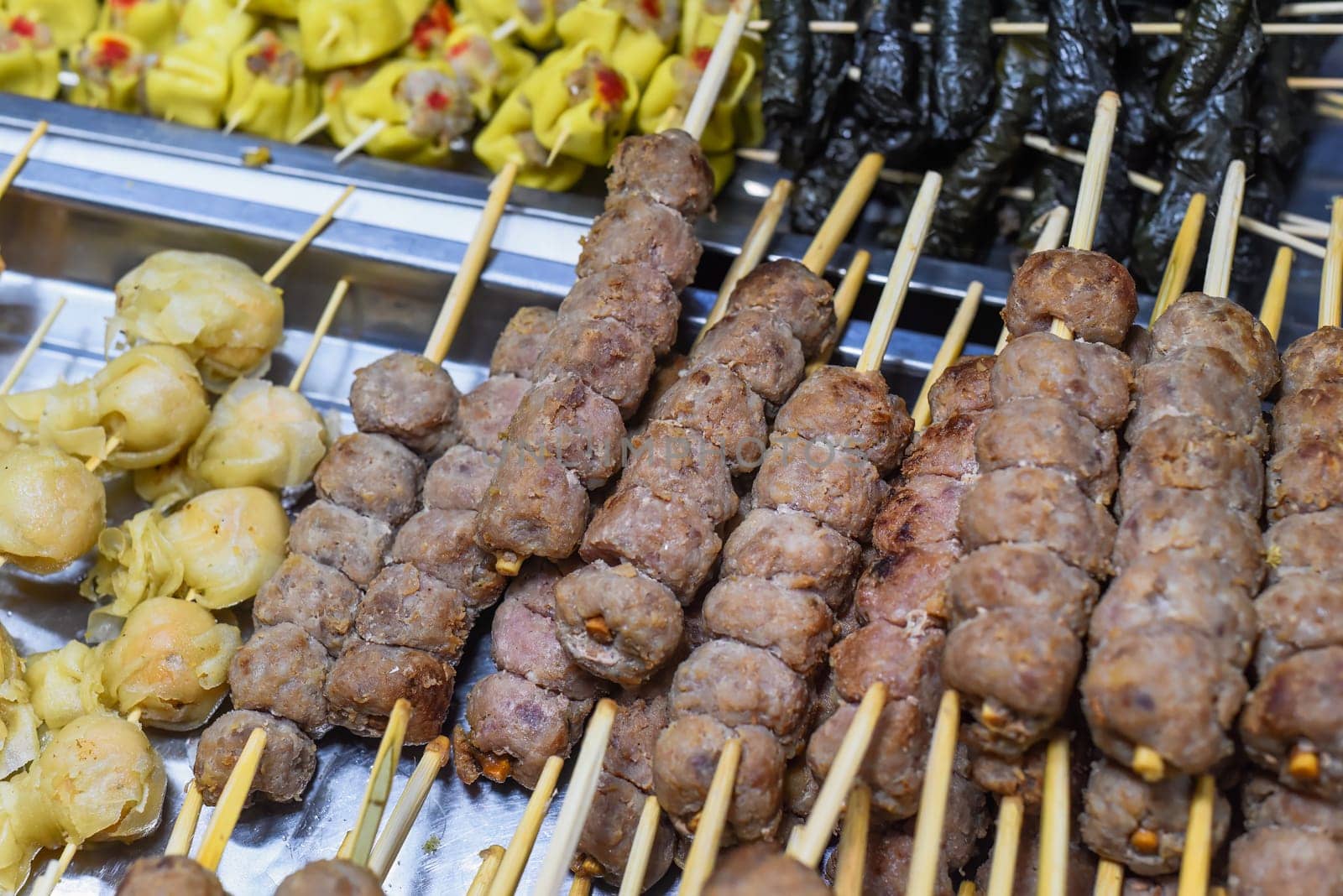 Many snacks and seafood in vietnamese night market in food festival, sign "beef ball, fish ball, price 10 000 dongs"