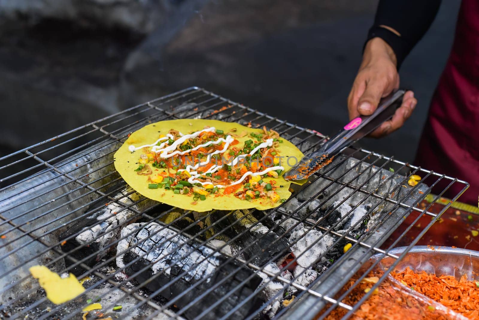 Grilled vietnamese pancake with eggs, sausages and sauces in vietnamese night market in food festival
