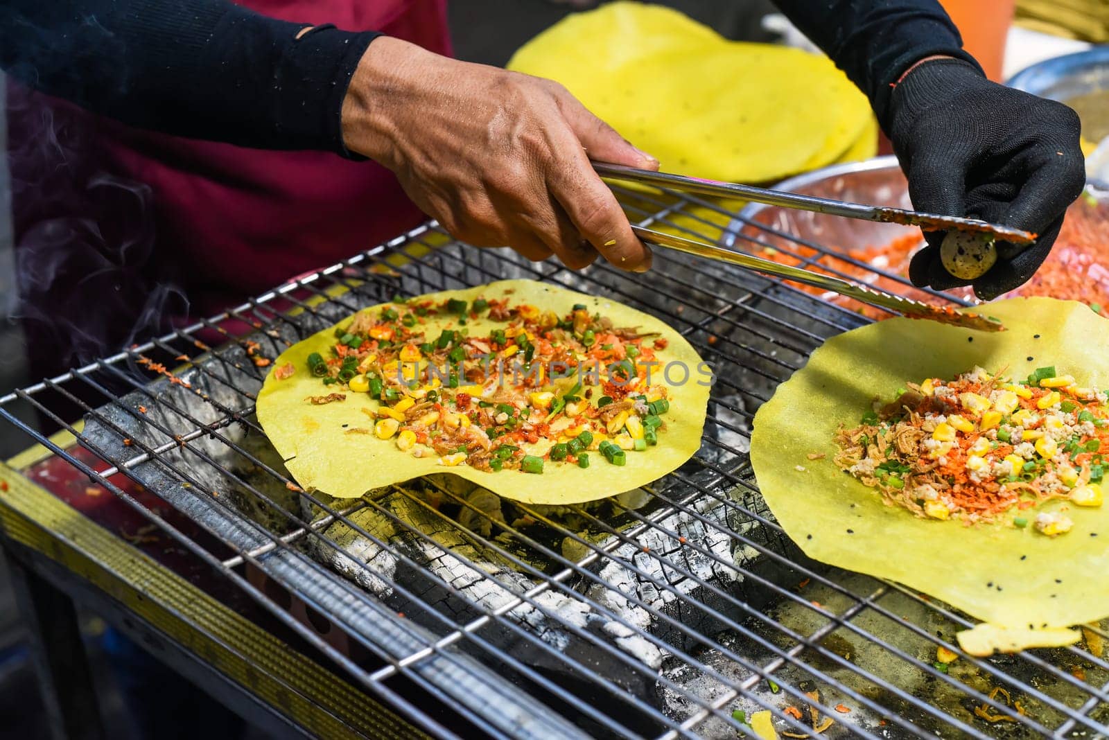 Grilled vietnamese pancake with eggs, sausages and sauces in vietnamese night market in food festival
