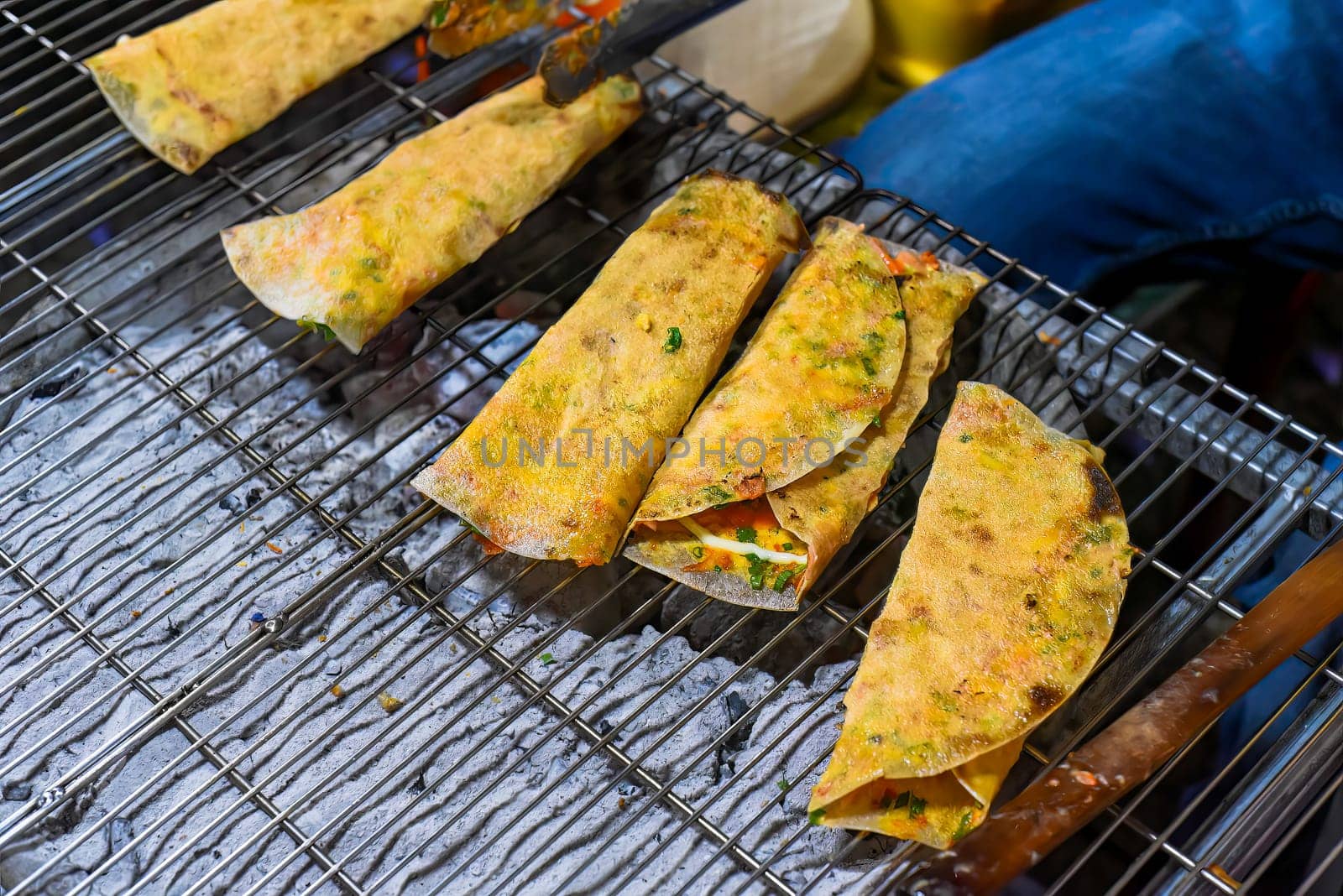 Grilled vietnamese pancake with eggs, sausages and sauces in vietnamese night market in Da Lat