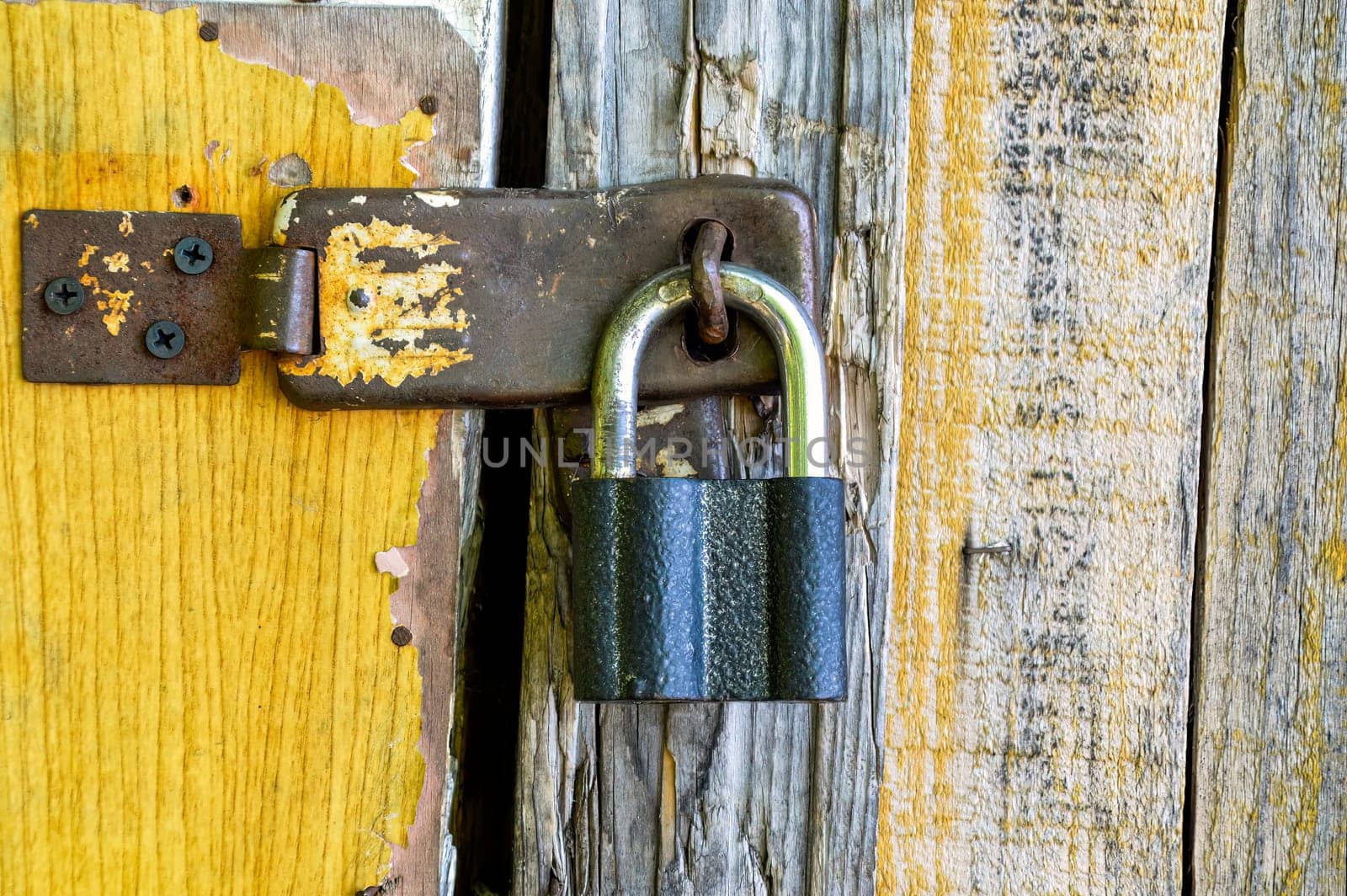 Old padlock hanging on a wooden shabby door