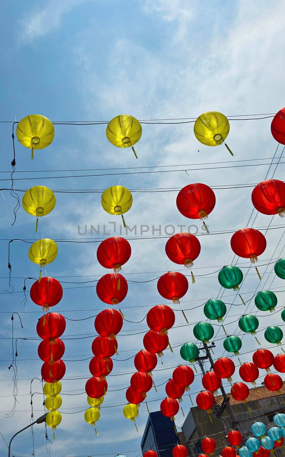 Vibrant red and yellow lanterns suspended across open balconies under a serene blue sky, representing festive celebrations of chinese new year and traditional cultural decor. good for background