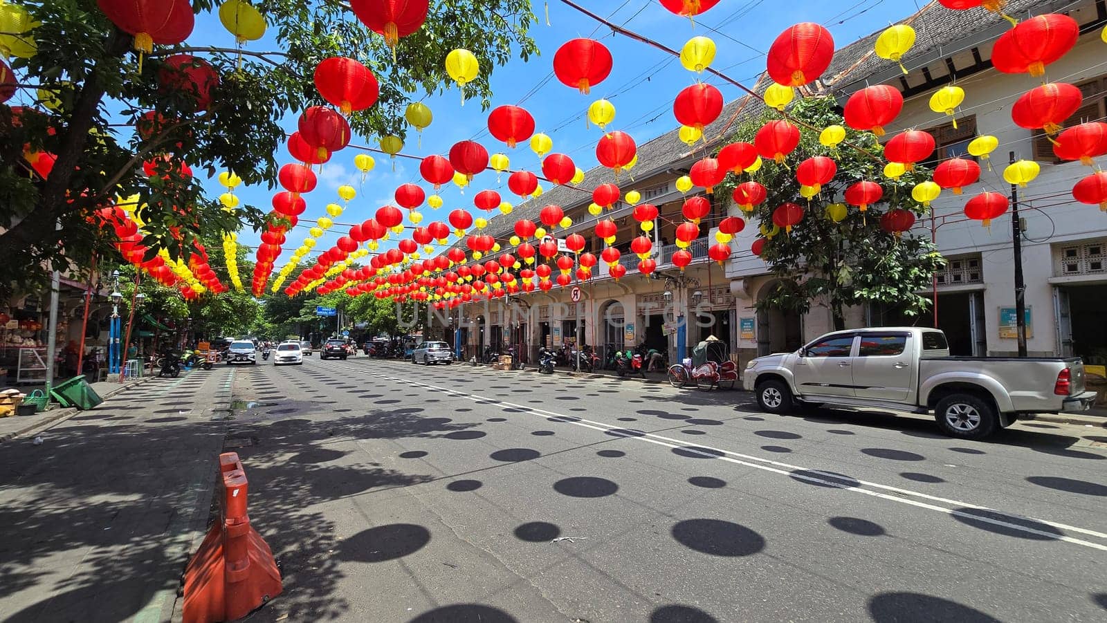 Vibrant red and yellow lanterns suspended across open balconies under a serene blue sky, representing festive celebrations of chinese new year and traditional cultural decor. good for background