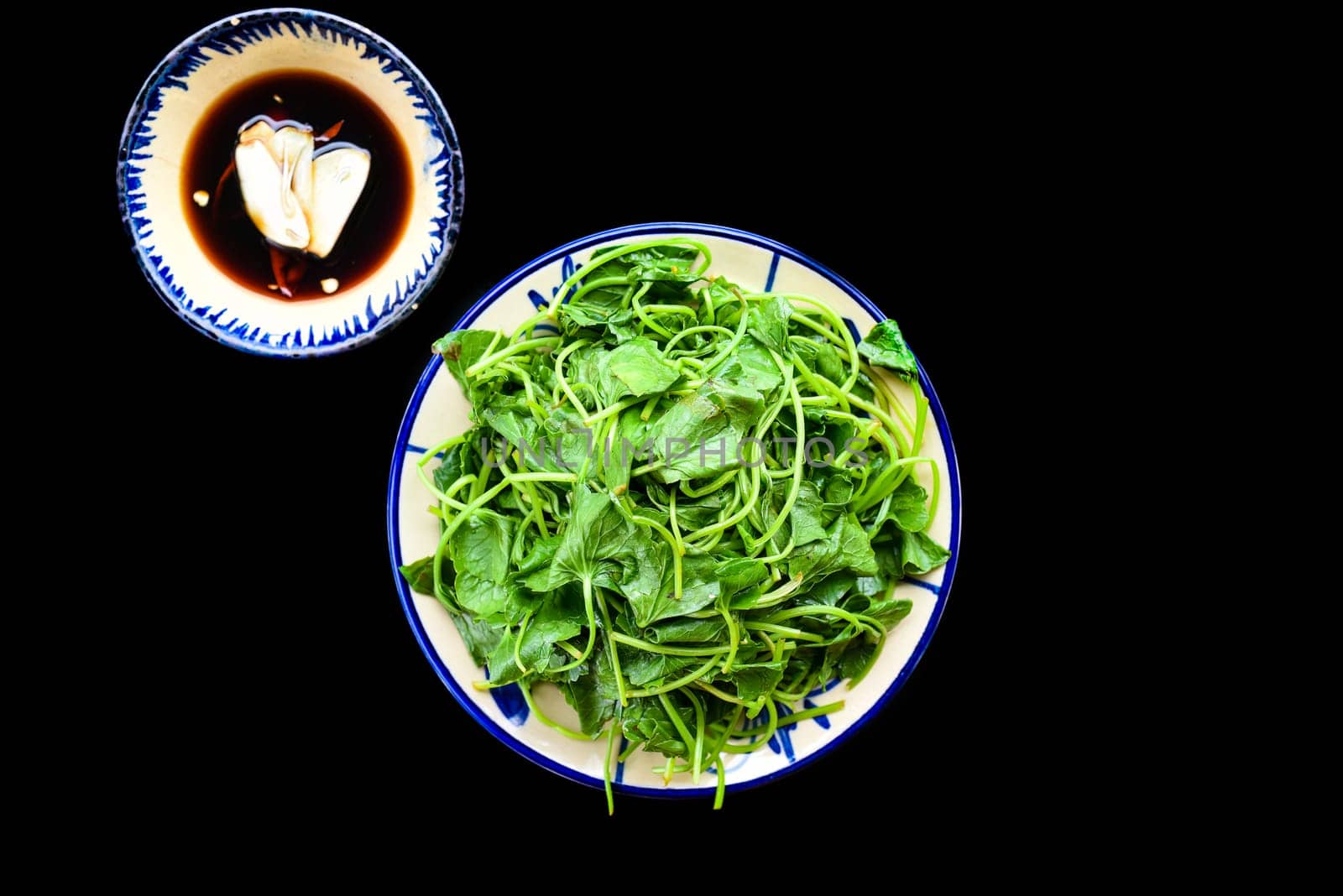 Vietnamese fried sweet potato leaves with garlic on black background