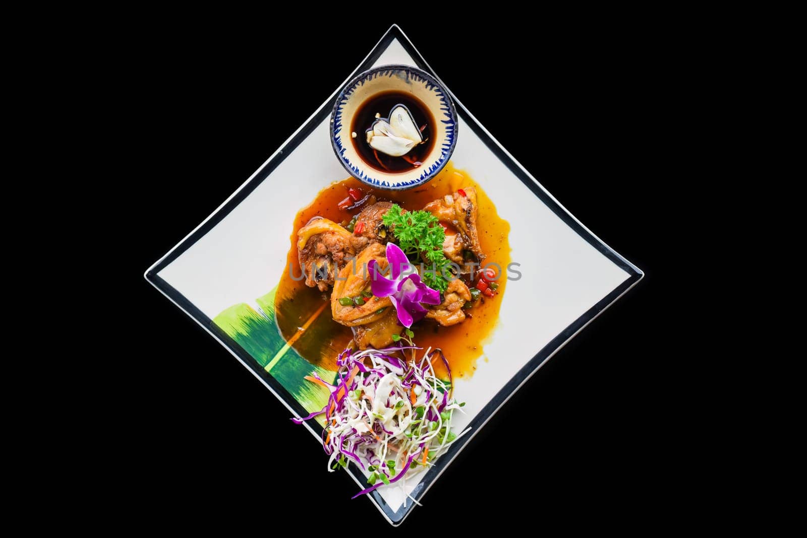 Stewed chicken with vegetables and sauce on black background top view