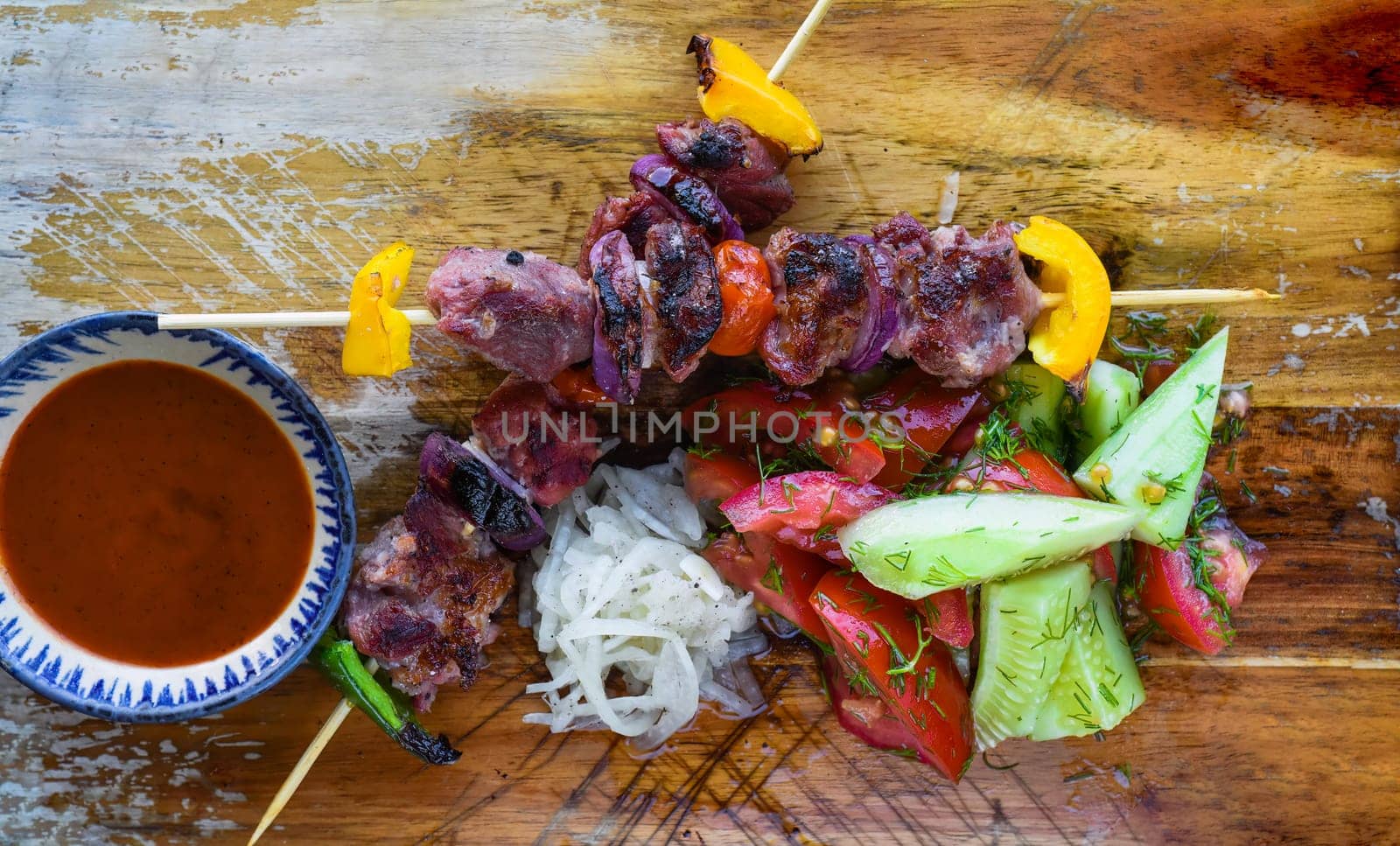 Pork skewers served with salad and sauce on black background top view