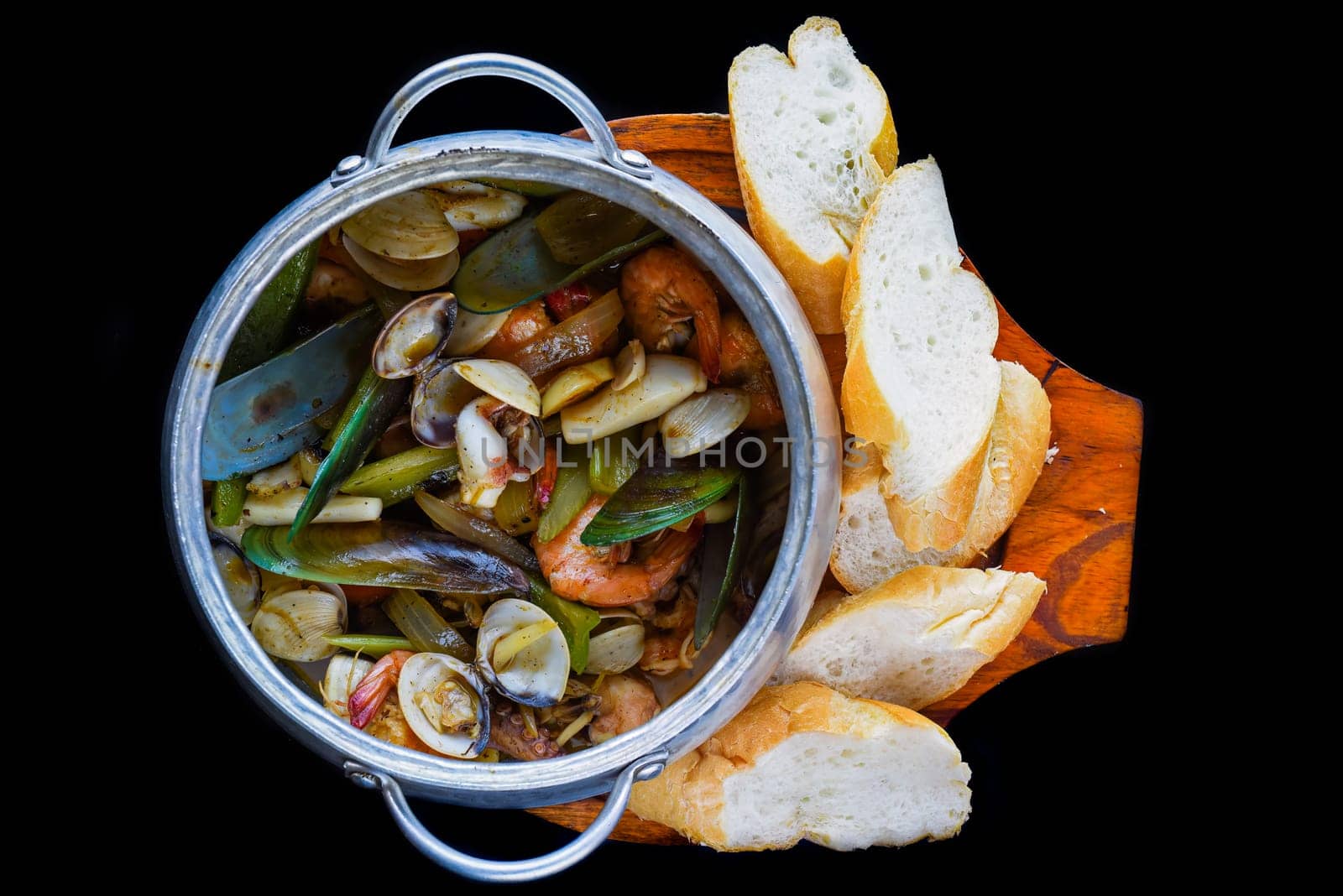 Sautéed seafood in pot close up isolated on black background side view