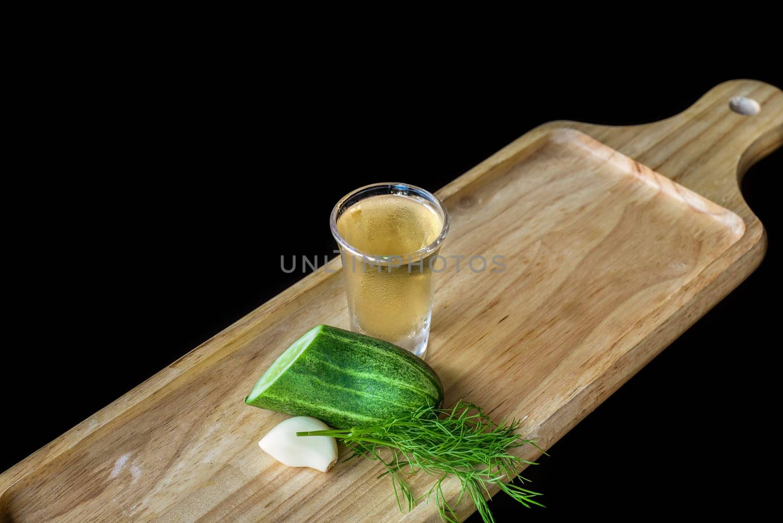 Alcohol shot made of cucumber, garlic and dill on wooden board with copy space