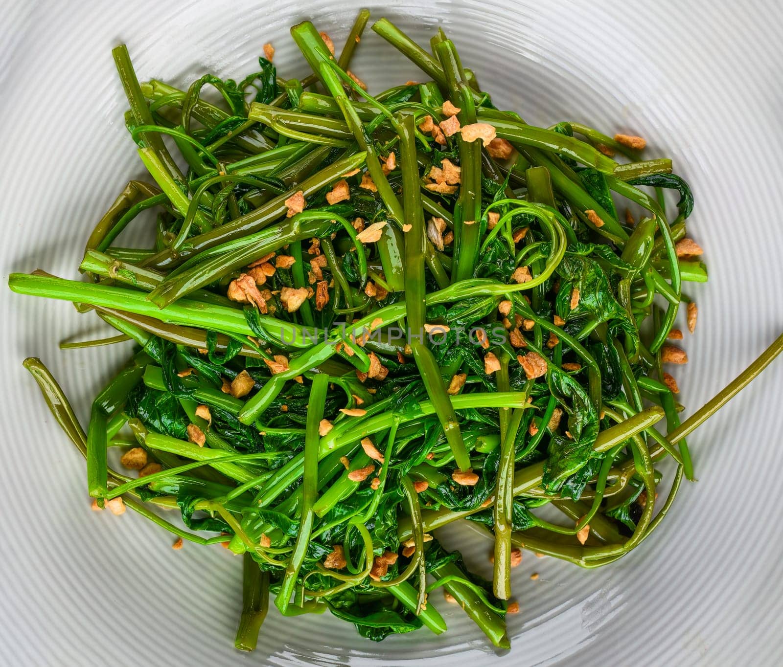 thai fried spinach on a white plate top view
