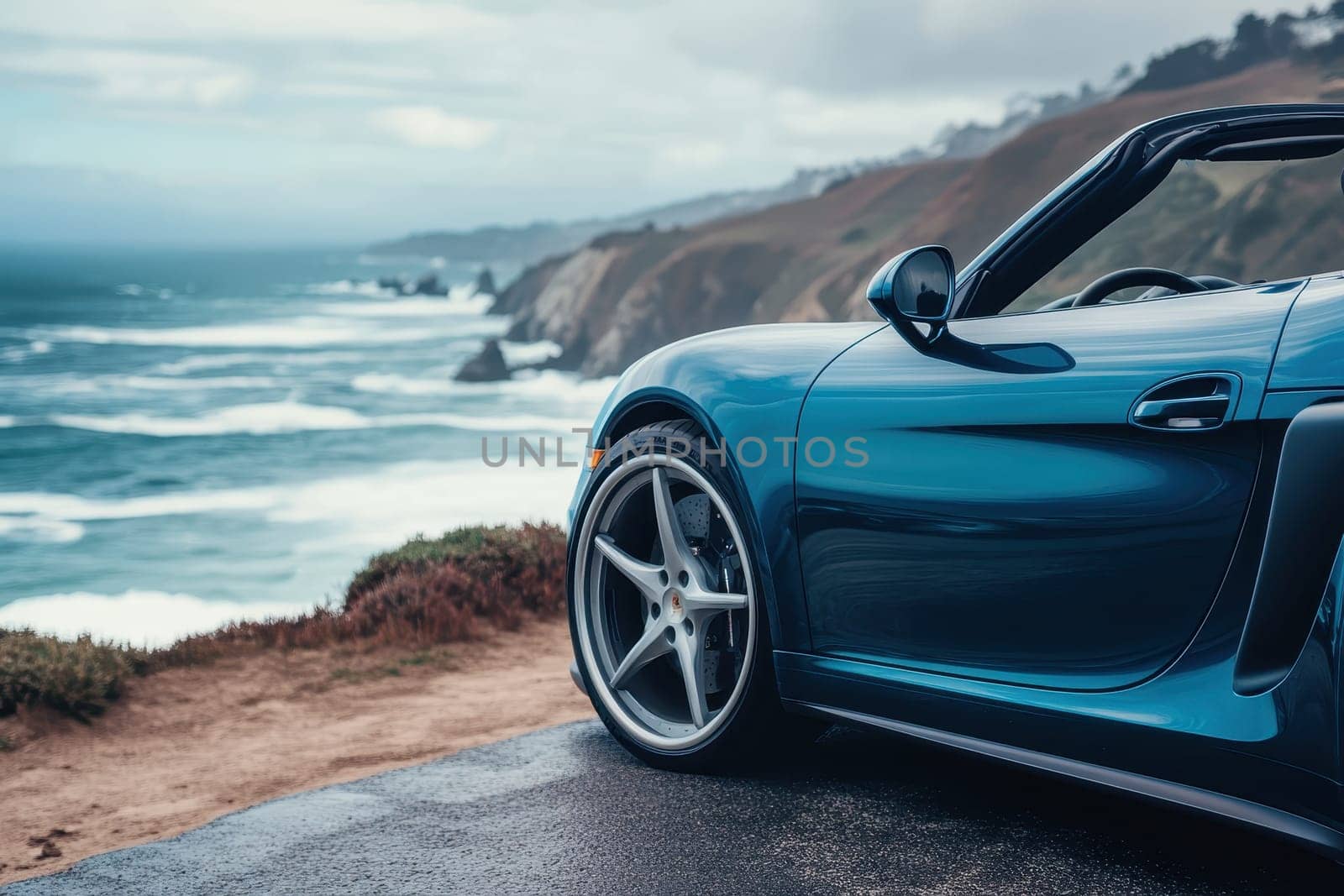 A blue sports car is parked on a road near the ocean. The car is shiny and has a sleek design. The ocean in the background creates a serene and calming atmosphere