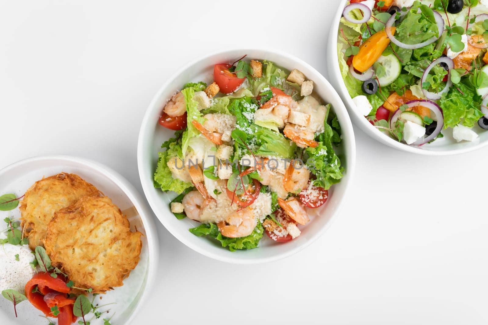 Vegetable salads and slavic draniki (potato pancakes) on white background