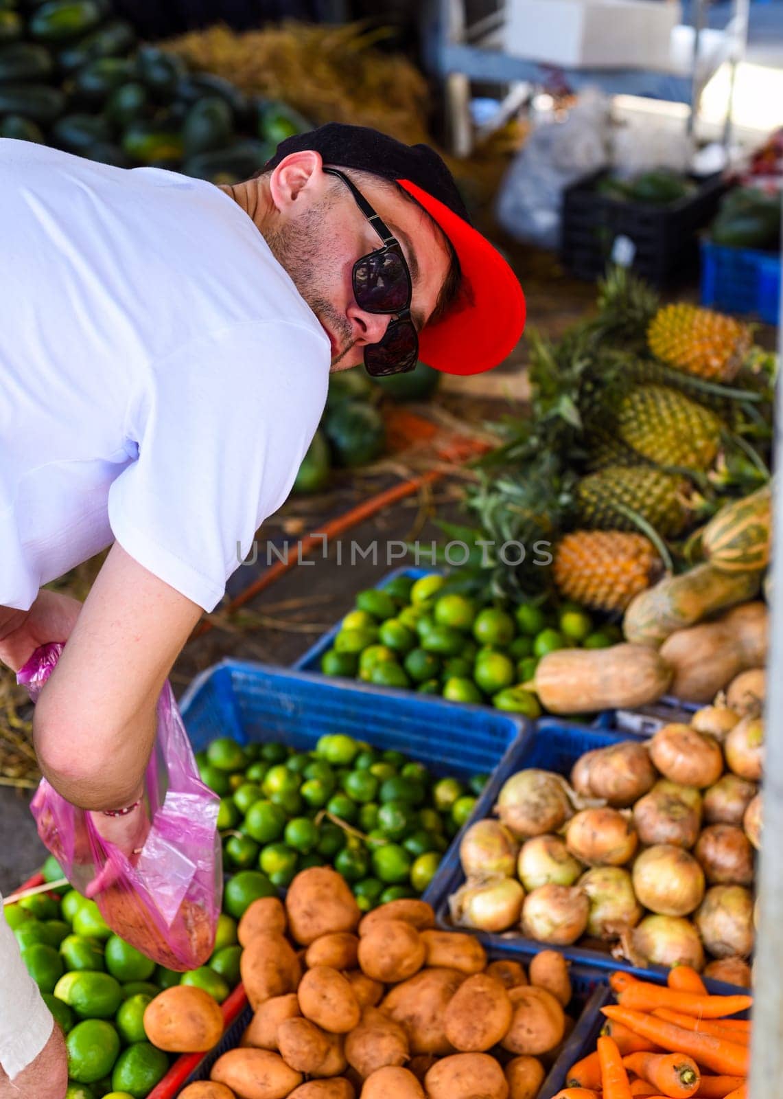 Young man choosing vegetables on the Vietnamese market Vinh Hai Nha Trang