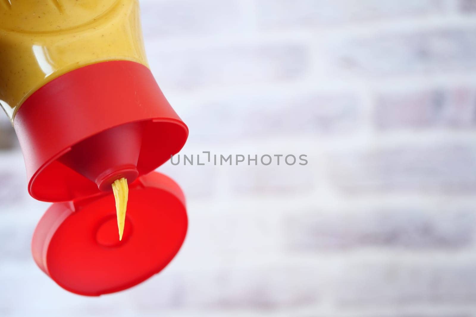 Yellow mustard is being squeezed from a bottle in a kitchen.