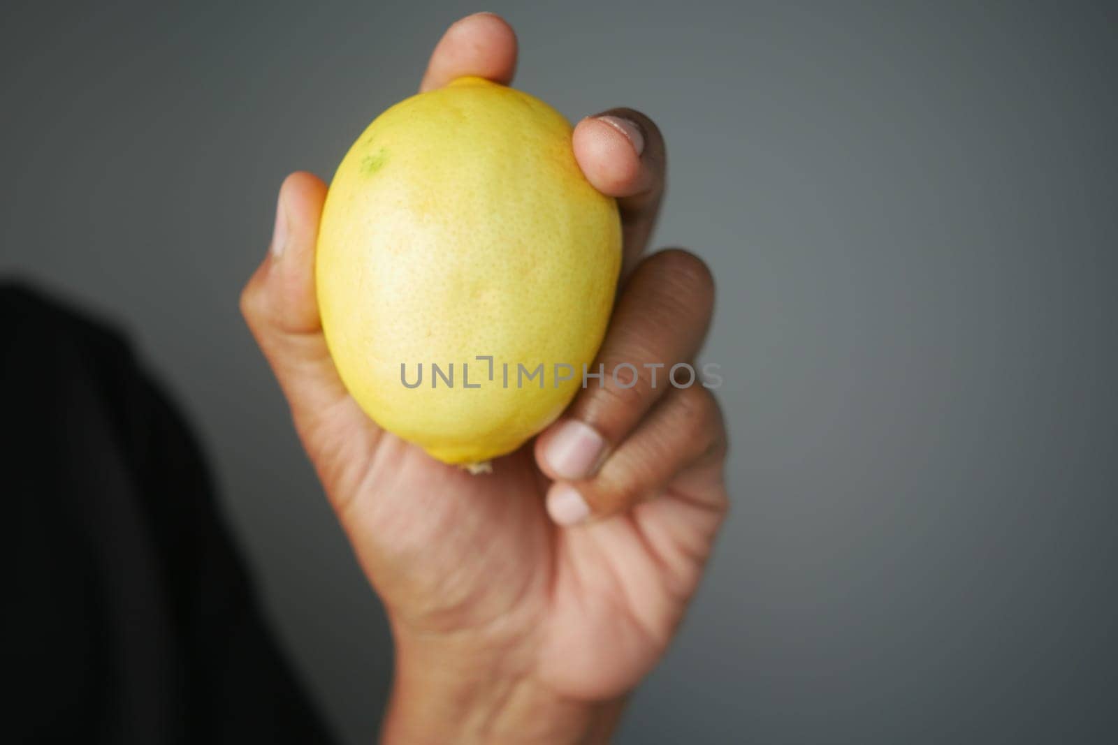 A person holds a ripe lemon close to the camera.
