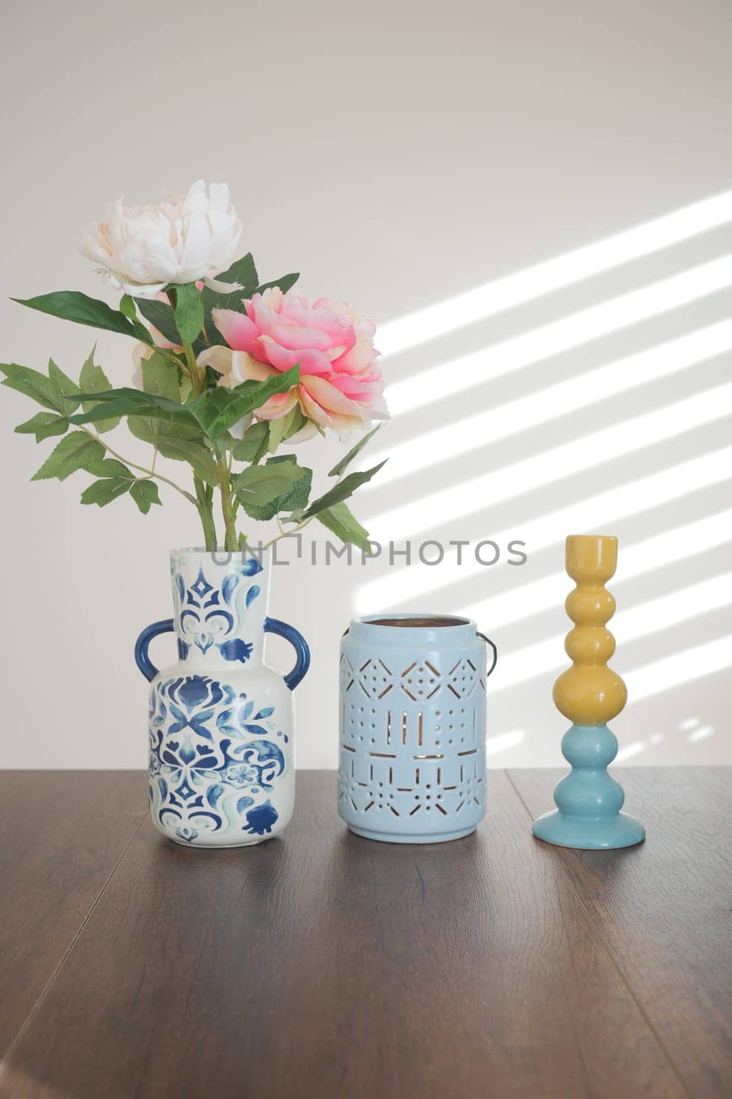 Colorful vases hold flowers on a well-lit table.