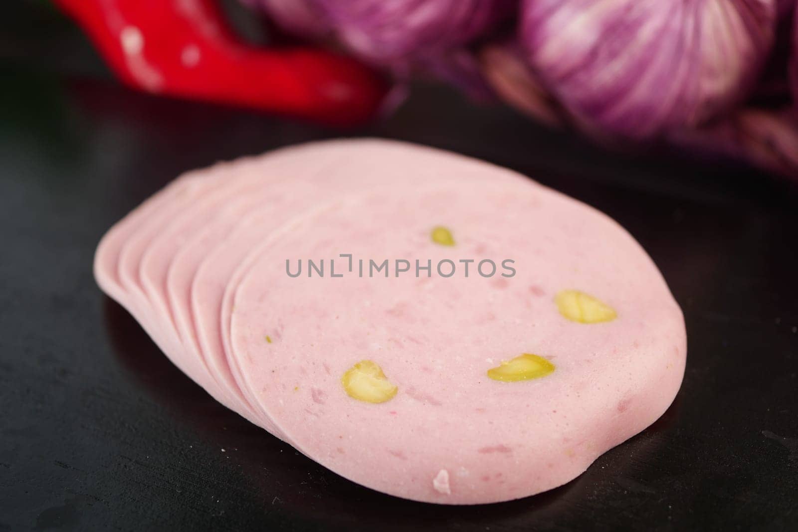 Slices of pink meat with pistachios are arranged neatly.