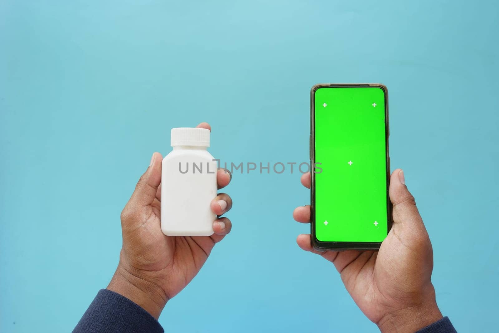 Person with white pill bottle and green phone.