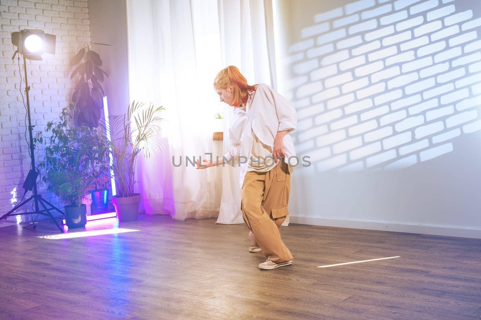 A dancer showcases their skill in a brightly-lit studio with creative lighting effects. Their movements convey emotion and artistry against a minimalist backdrop.