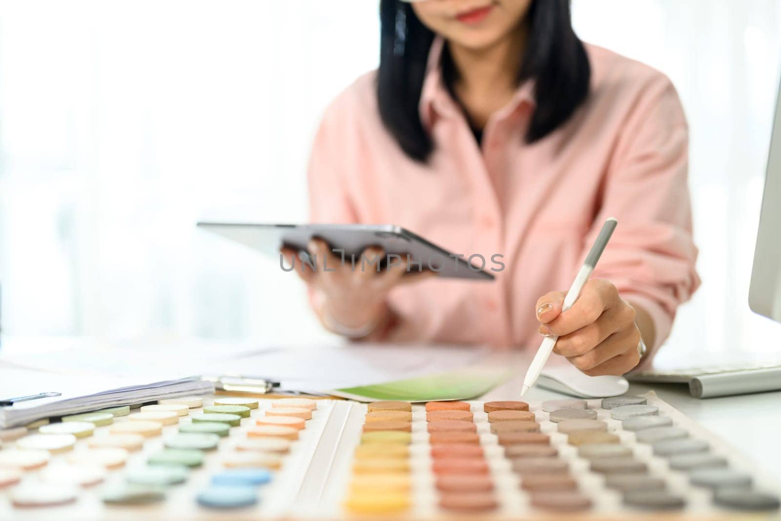 Interior designer holding digital tablet selecting color tones for a project.