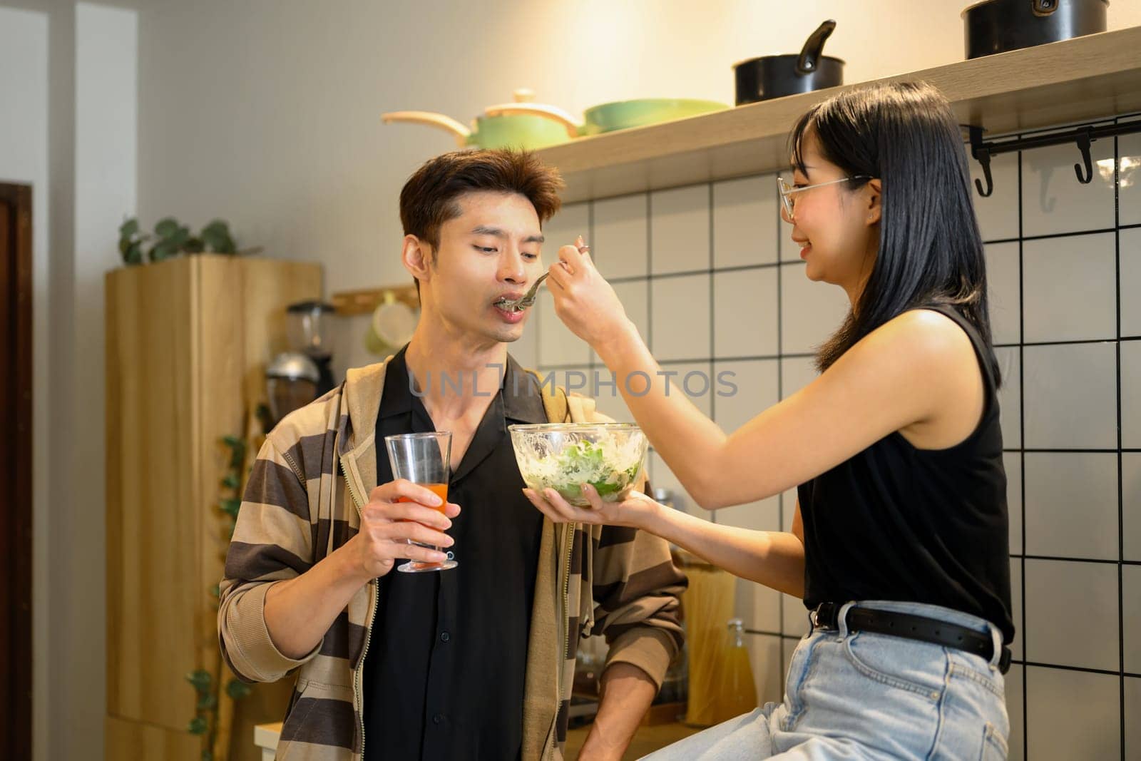 Happy young couple sharing a healthy salad in the kitchen.