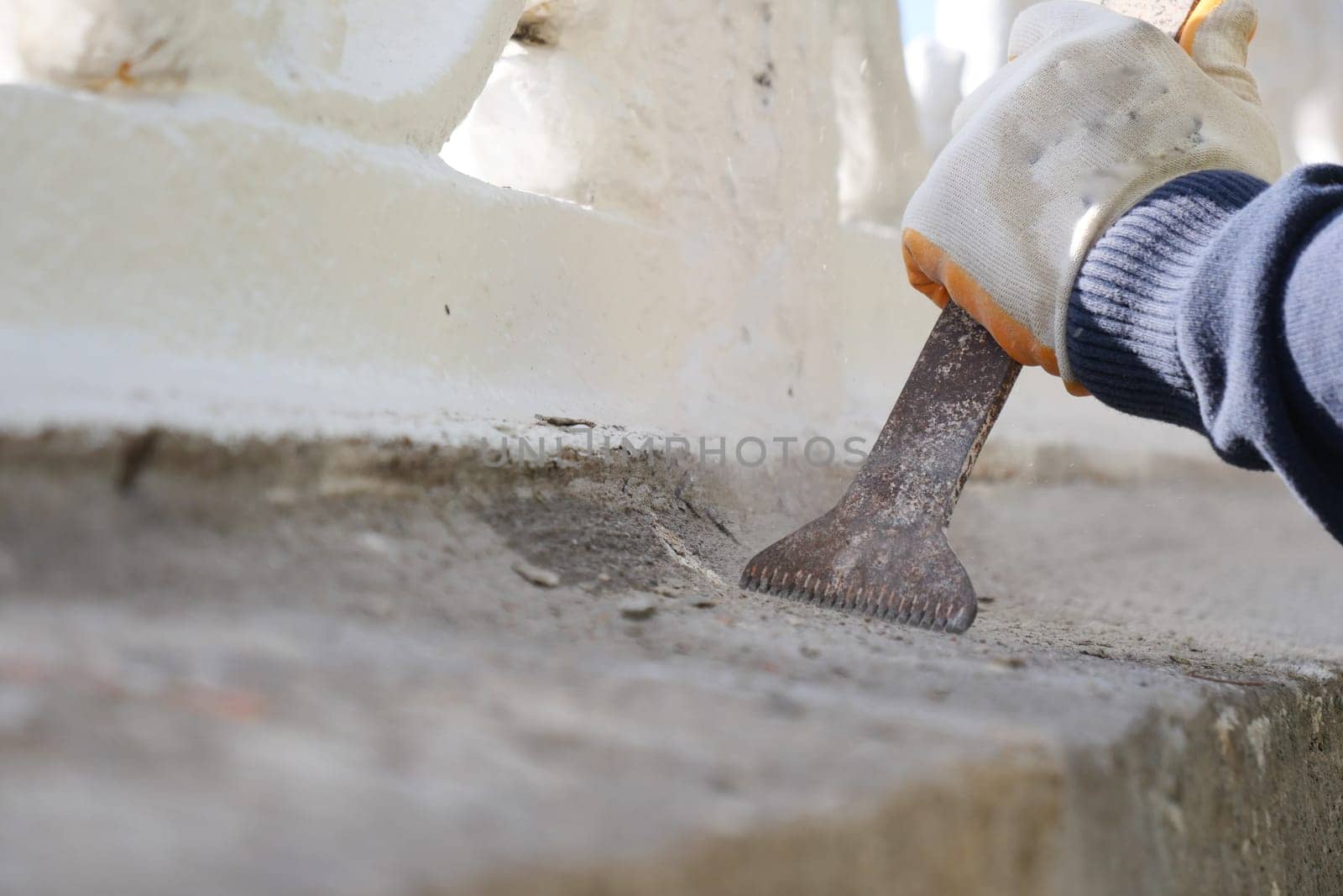 A worker carefully repairs a historic structure with tools in hand.