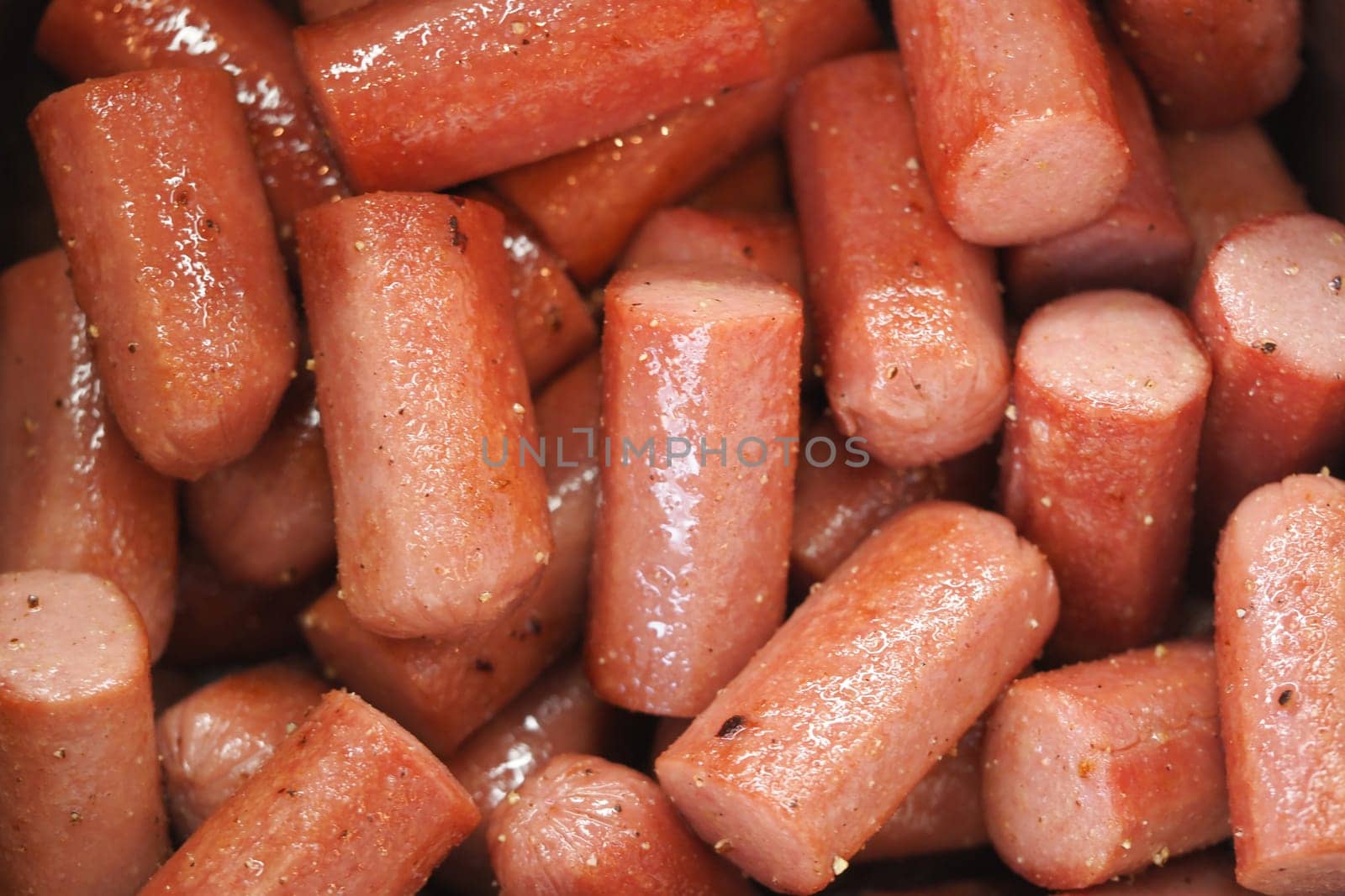 Juicy, cooked sausages are stacked closely in a container.